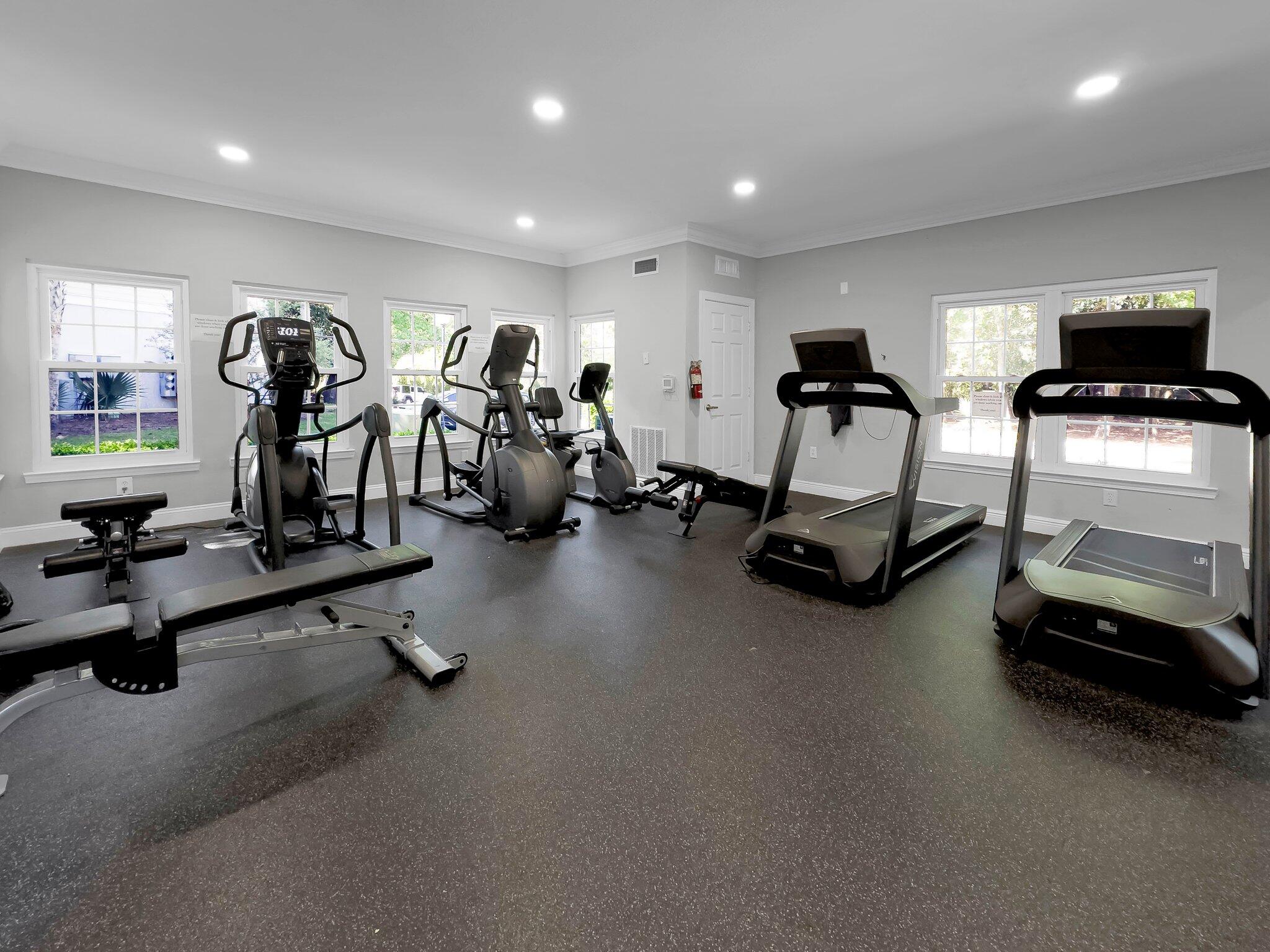 Fitness room with treadmills, elliptical machines, and exercise bikes by large windows.