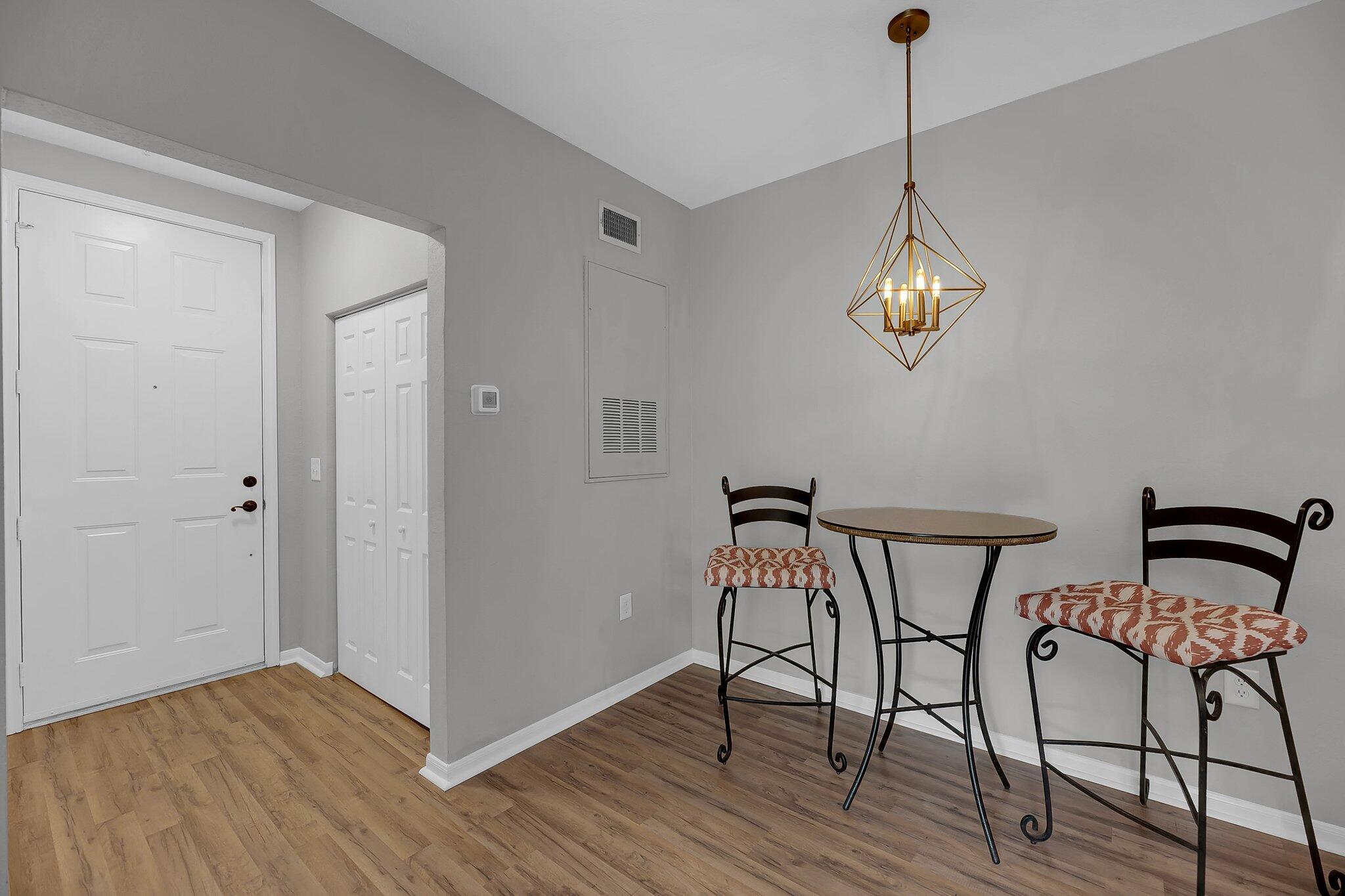 Furnished entryway with wood-look flooring, a round table, two chairs, and a brass pendant light.
