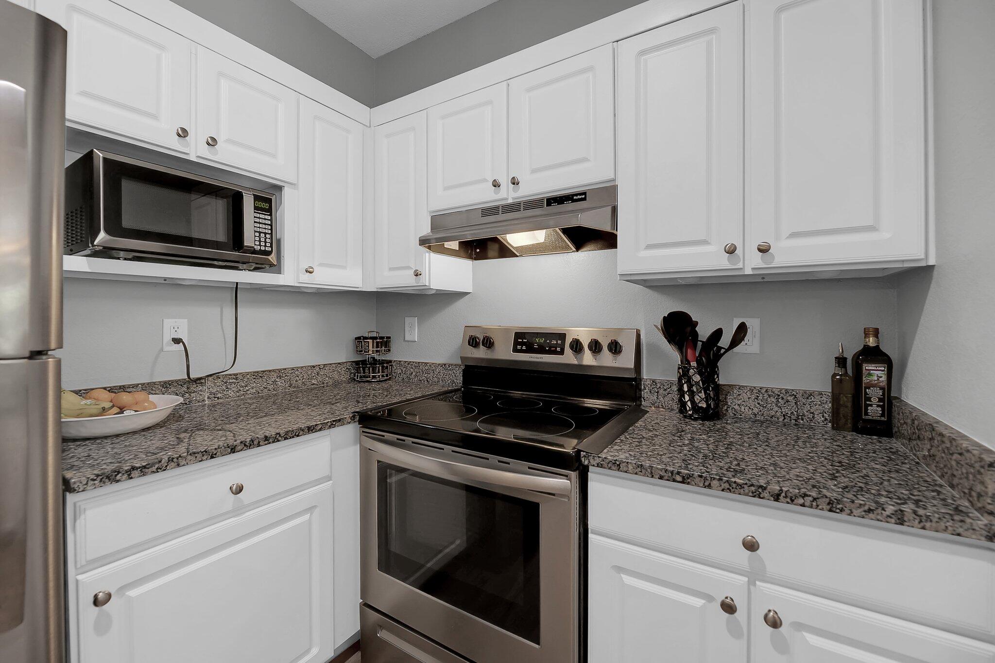 Kitchen with white cabinets, speckled granite counters, and stainless steel appliances.