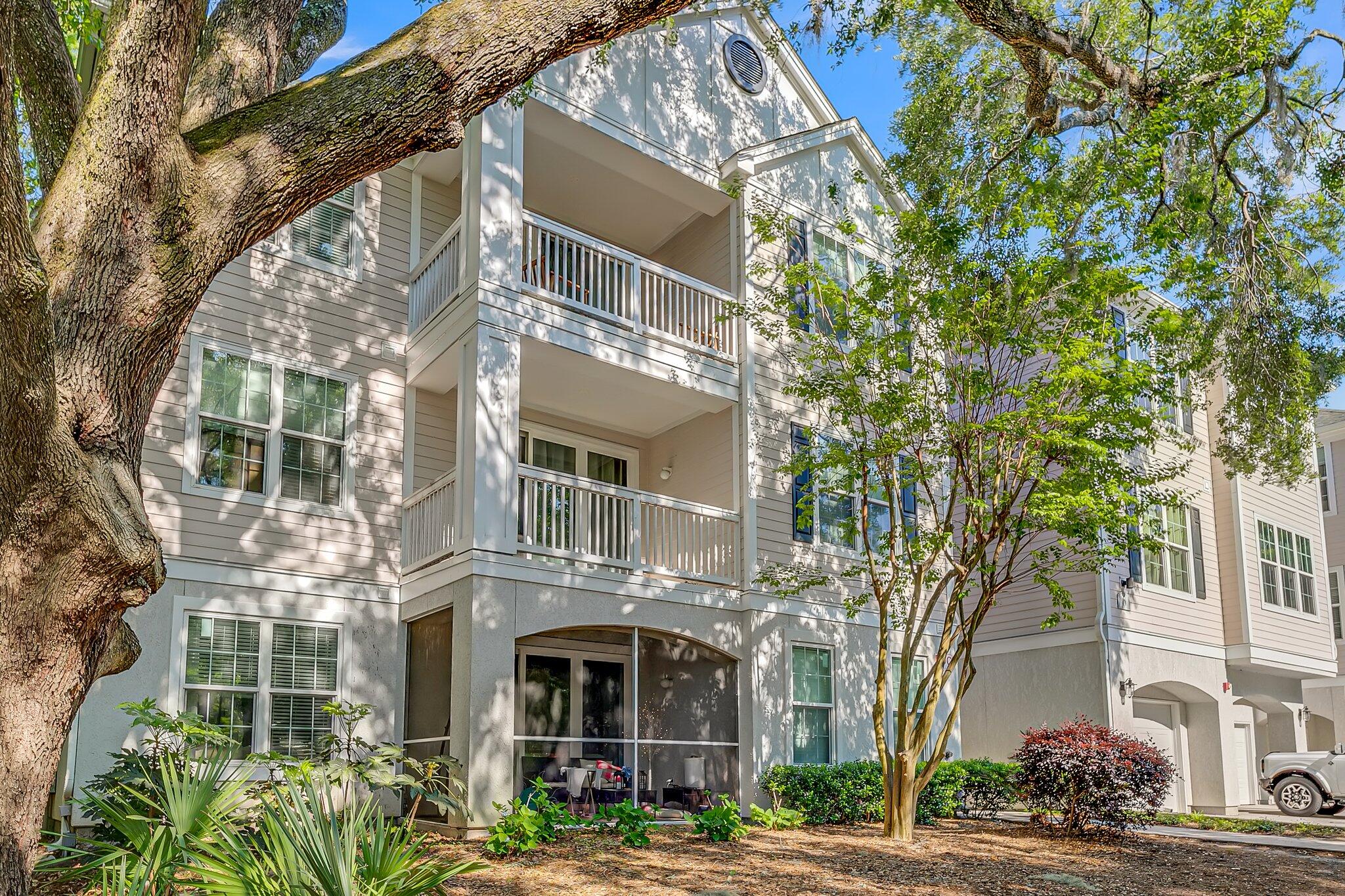 Multi-story residential building with stacked balconies framed by mature trees.