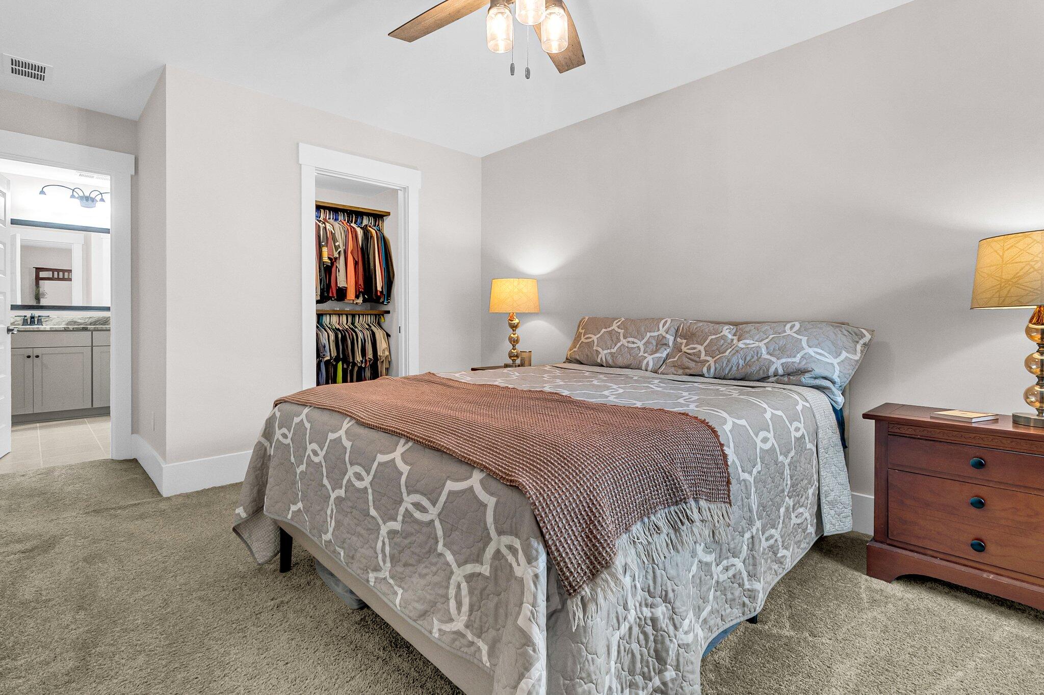 Bedroom with patterned bedding, an open clothes closet, and an adjoining bathroom.
