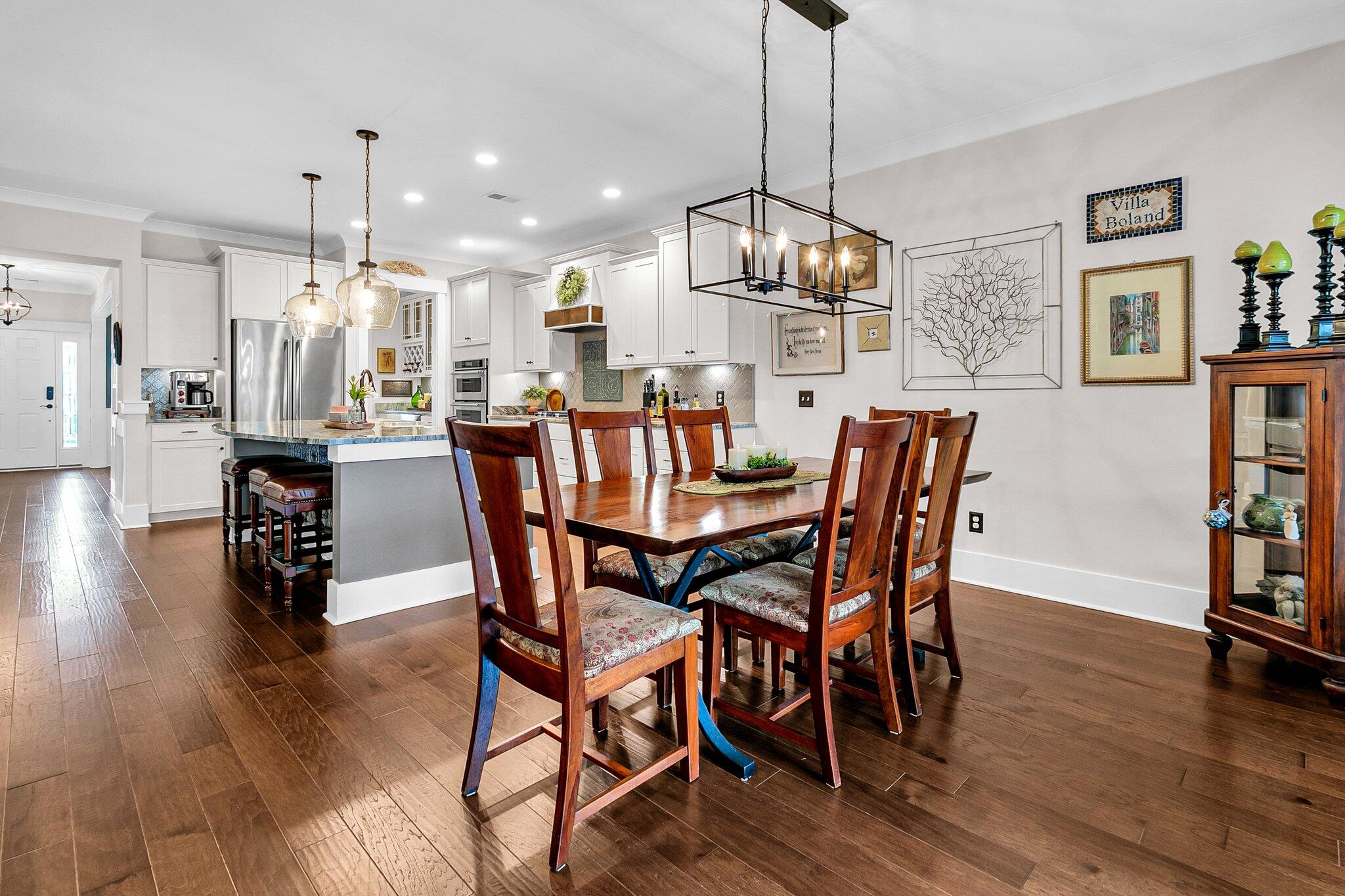 Open-plan kitchen and dining area with white cabinets, a kitchen island, and a large wooden dining table.