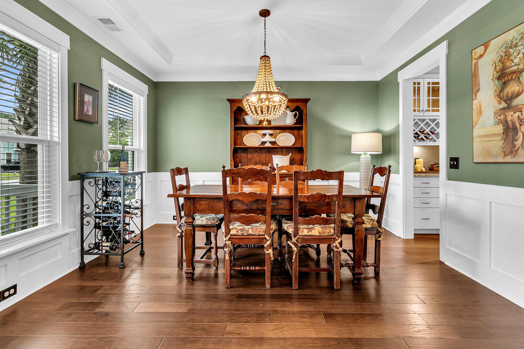 Dining room with a carved wood table beneath a crystal chandelier and a kitchen doorway.