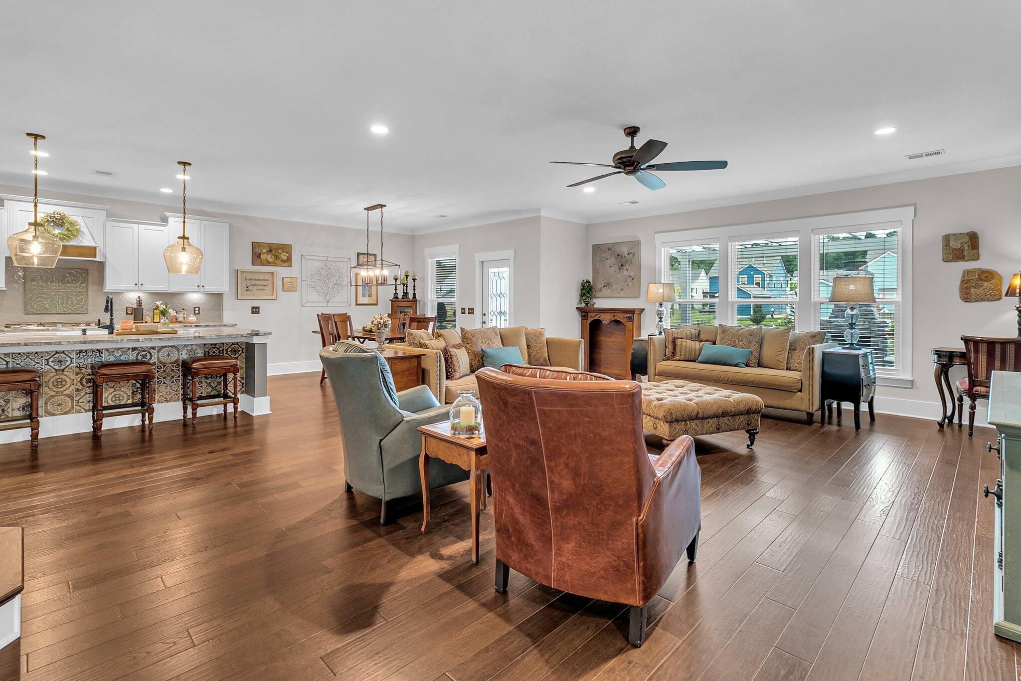 Open-plan living room and kitchen with patterned island tiles, dark wood floors, and large windows.