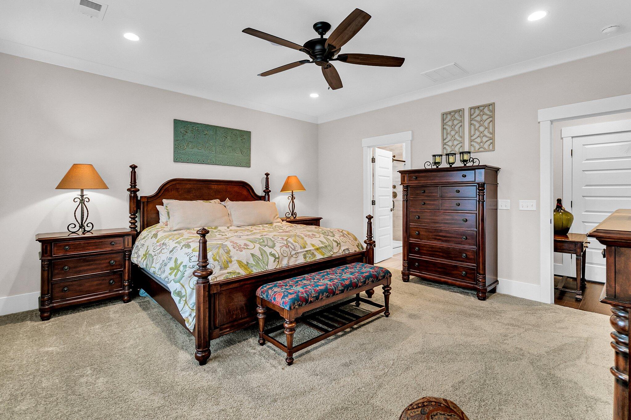 Furnished bedroom with a dark wood bed, floral quilt, matching dresser, and patterned bench.