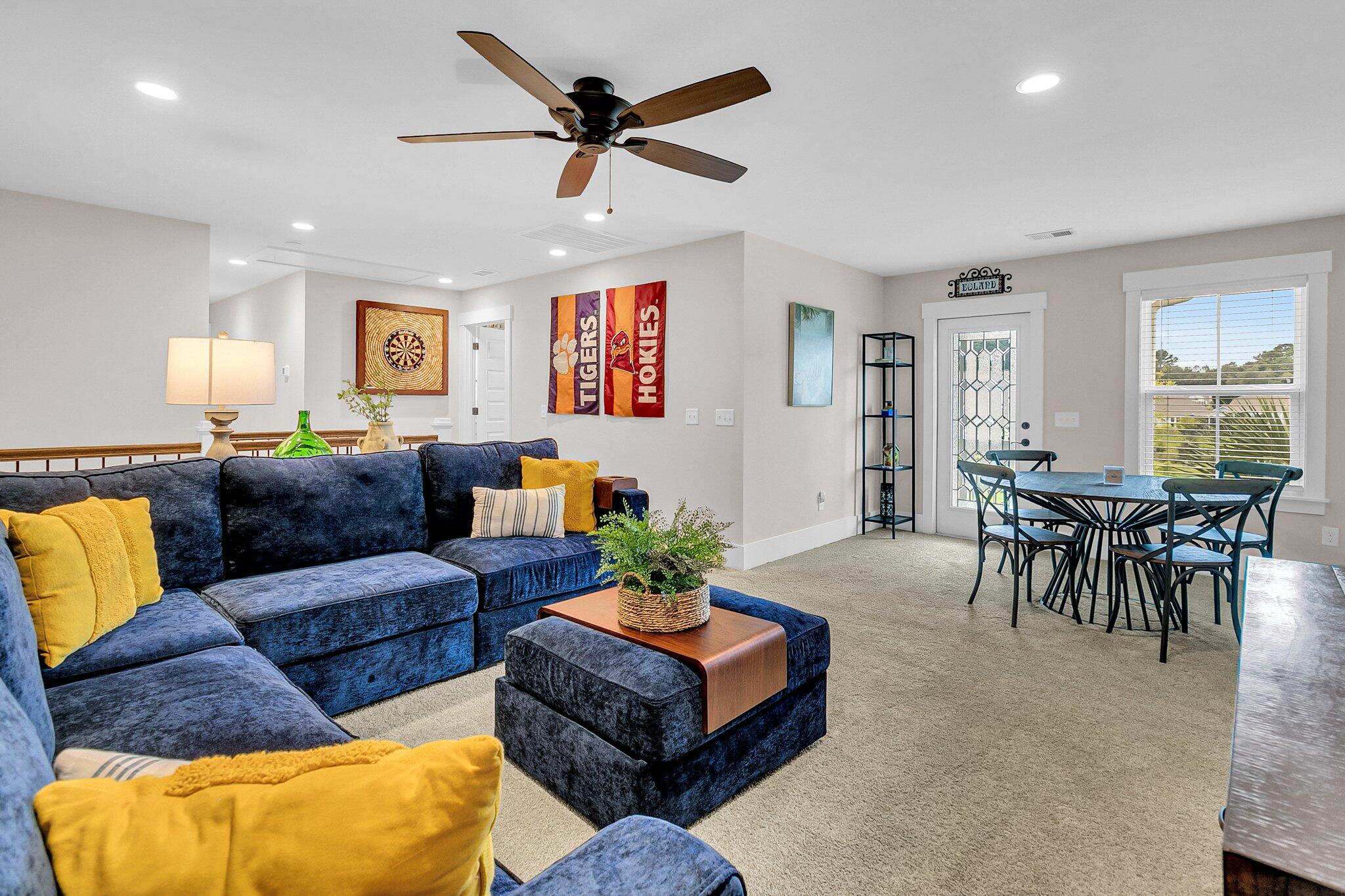Open-plan living and dining room with a navy sectional, yellow cushions, and sports banners.