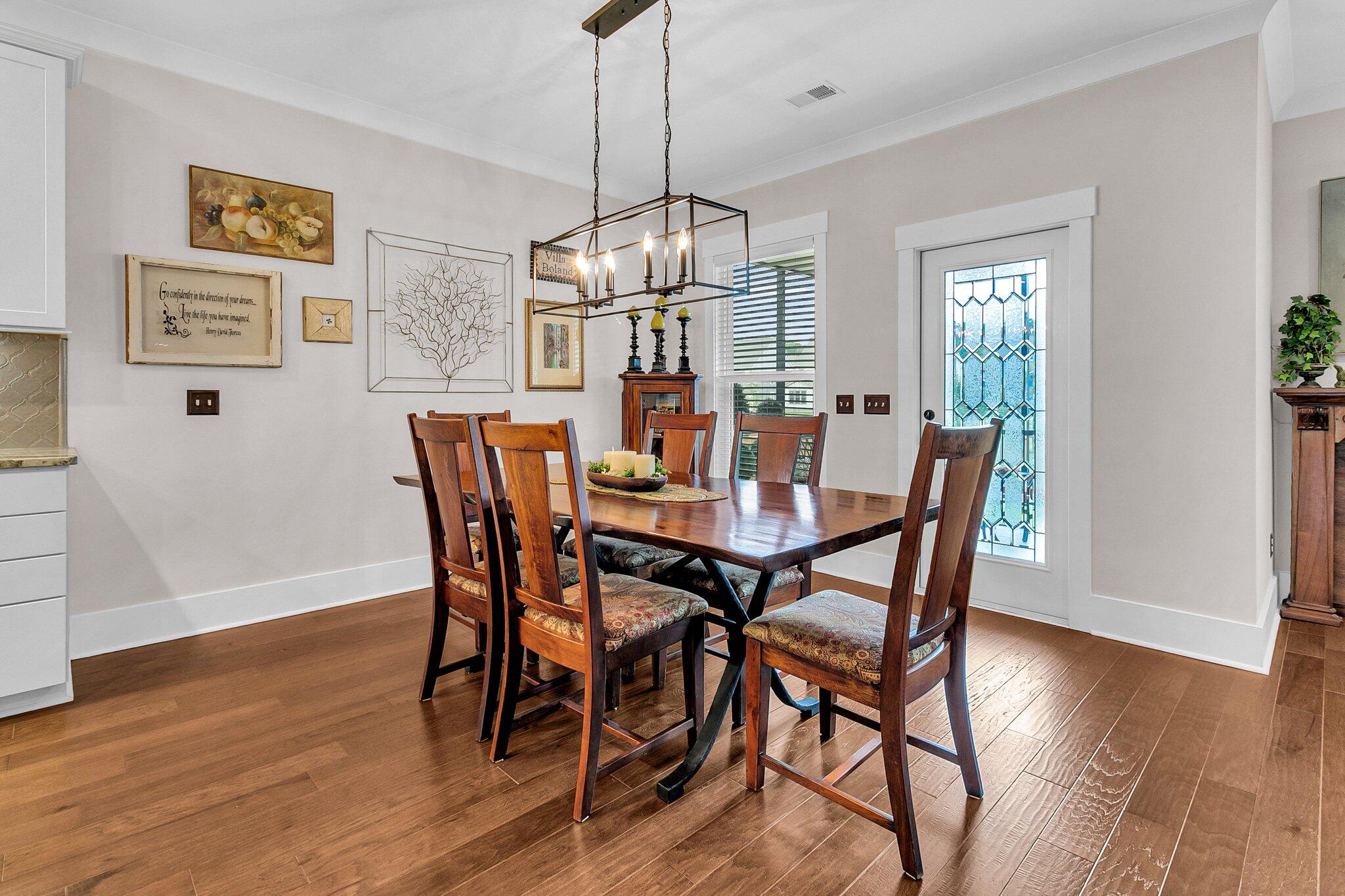 Dining room with a dark wood table, hardwood floors, and a geometric stained-glass door.