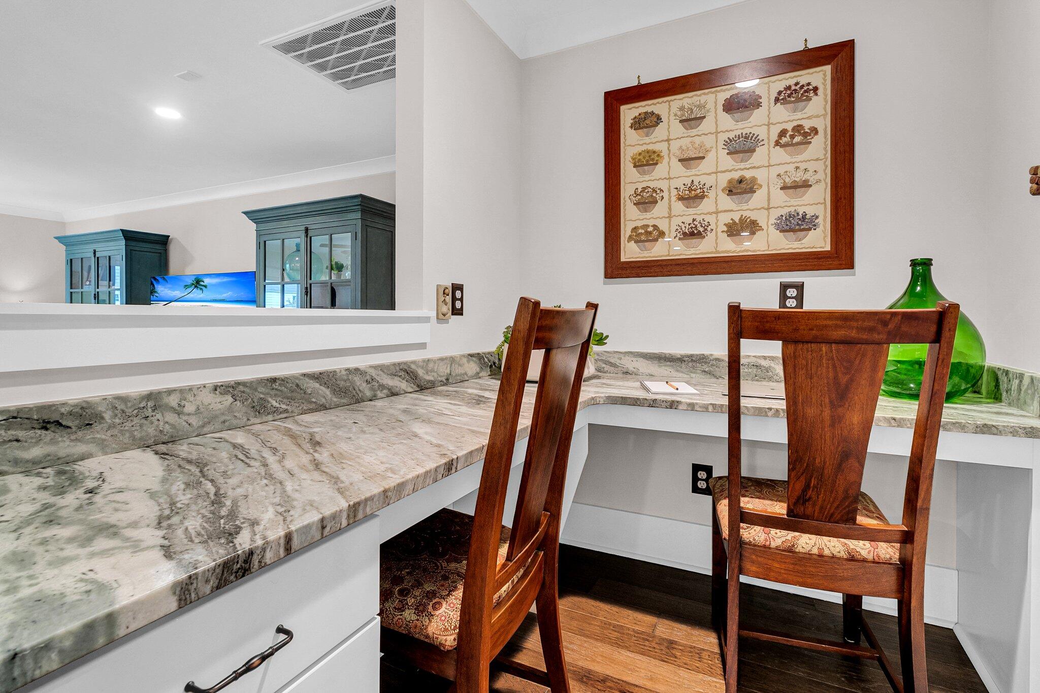 Marble counter with two wooden chairs and glass-front cabinets beyond a pass-through.
