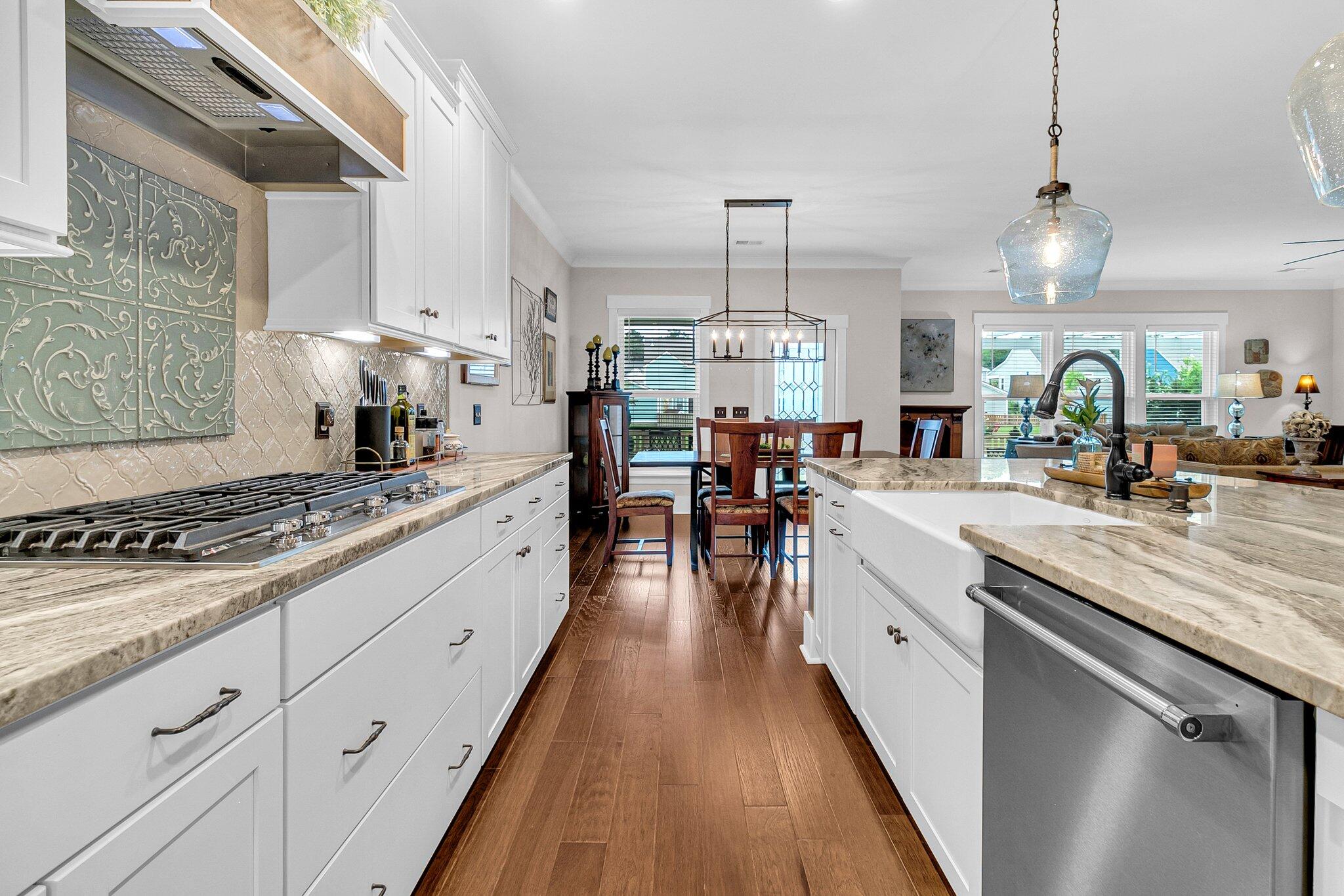 Kitchen with white cabinets, granite counters, gas cooktop, and dining area beyond.