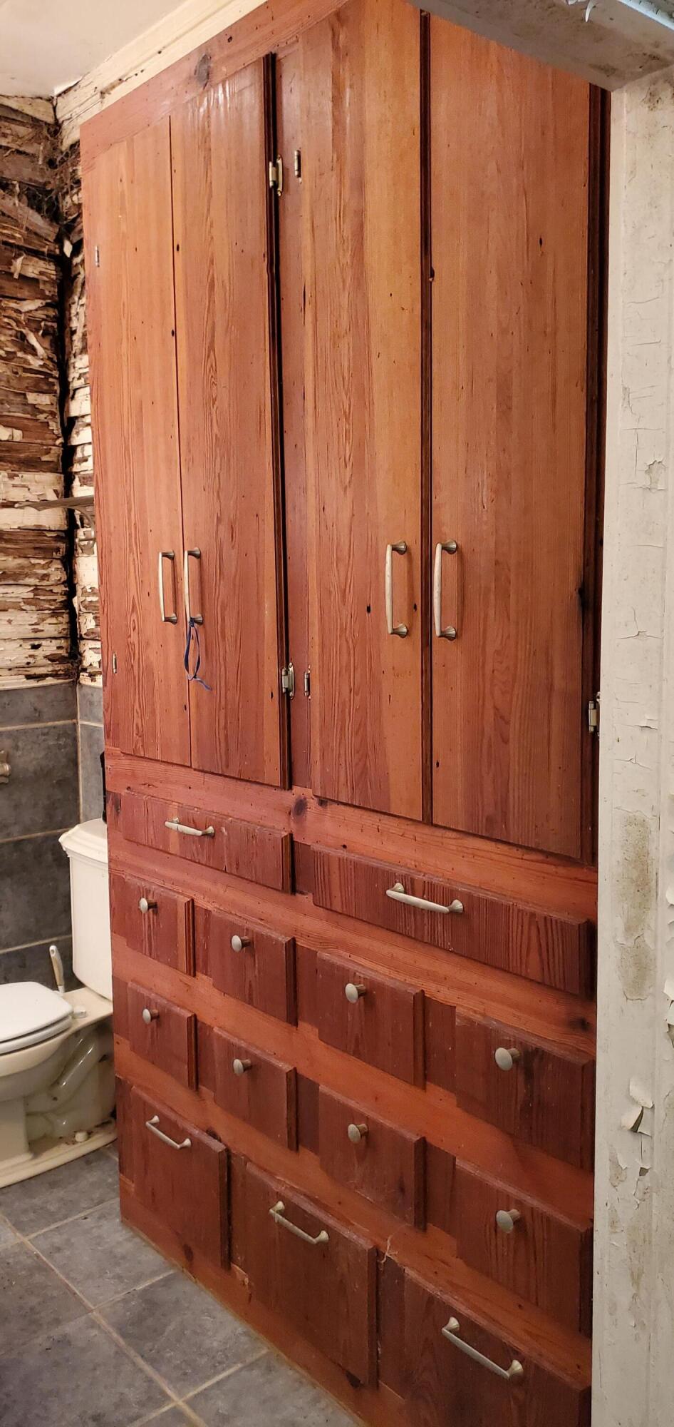 Bathroom with a tall reddish-brown built-in cabinet and a toilet.