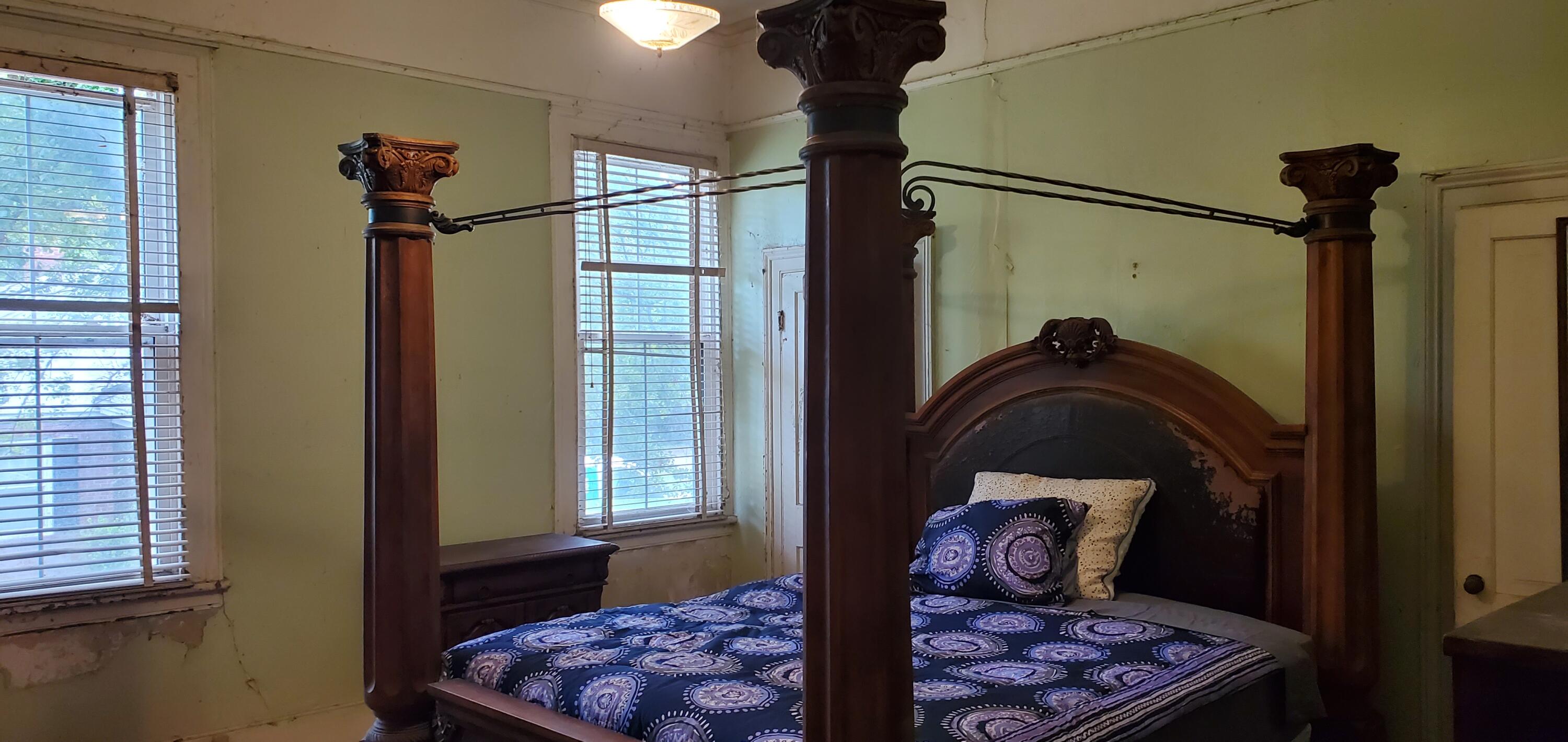 Bedroom with an ornate dark wood four-poster bed and blue patterned bedding.