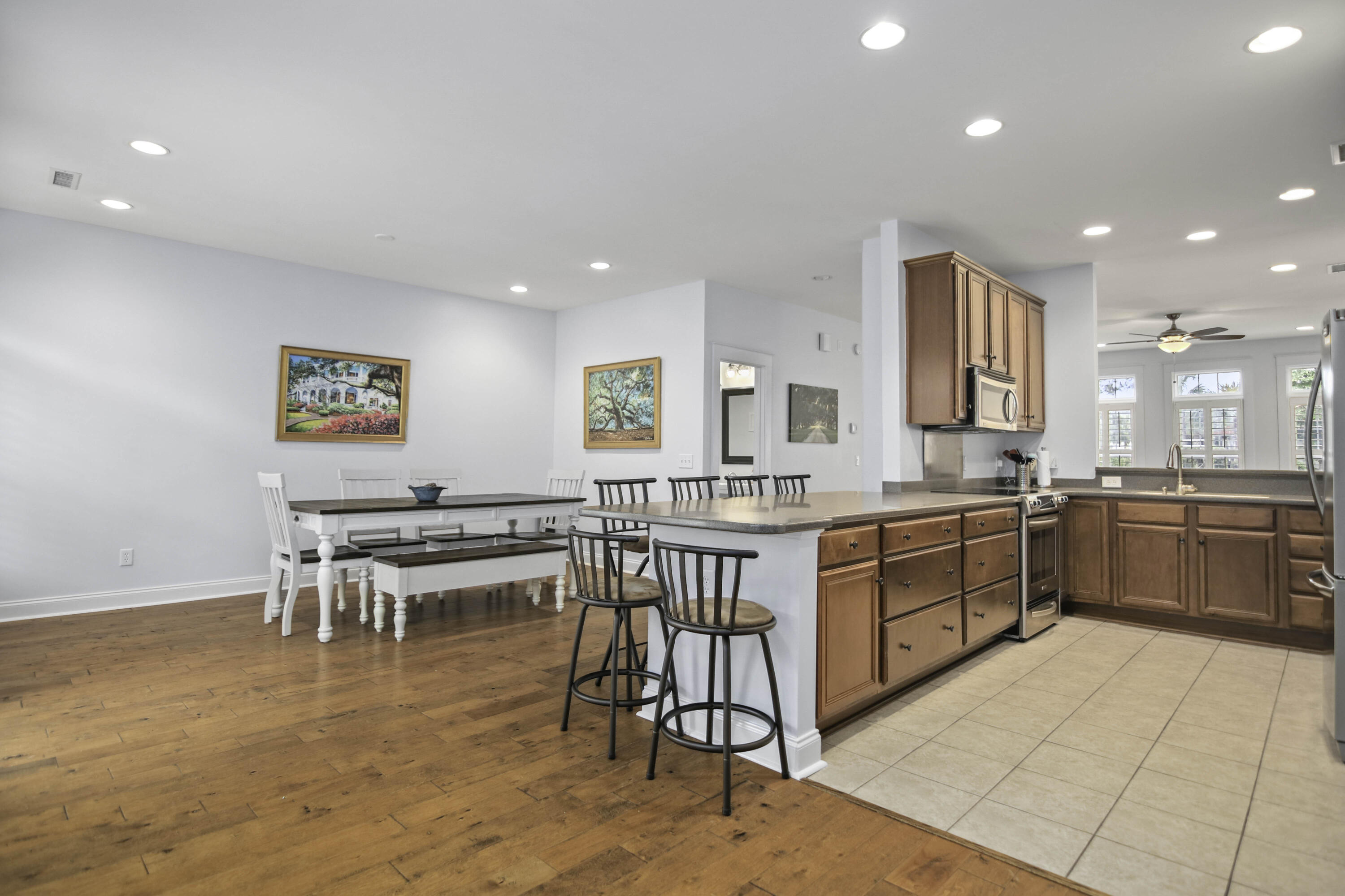 Open kitchen and dining area with a large island, warm wood cabinets, stainless steel appliances, and hardwood floors.