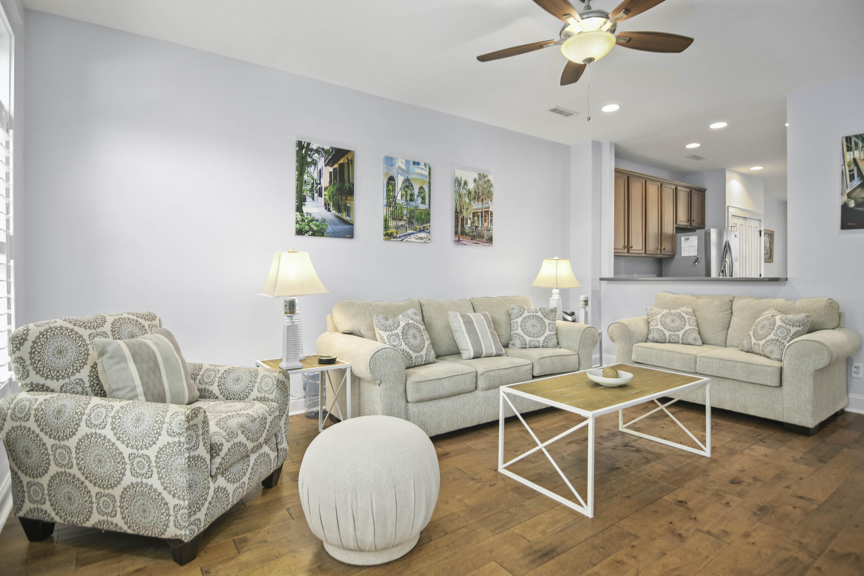 Furnished living room with beige sofas, a patterned armchair, and warm wood flooring.