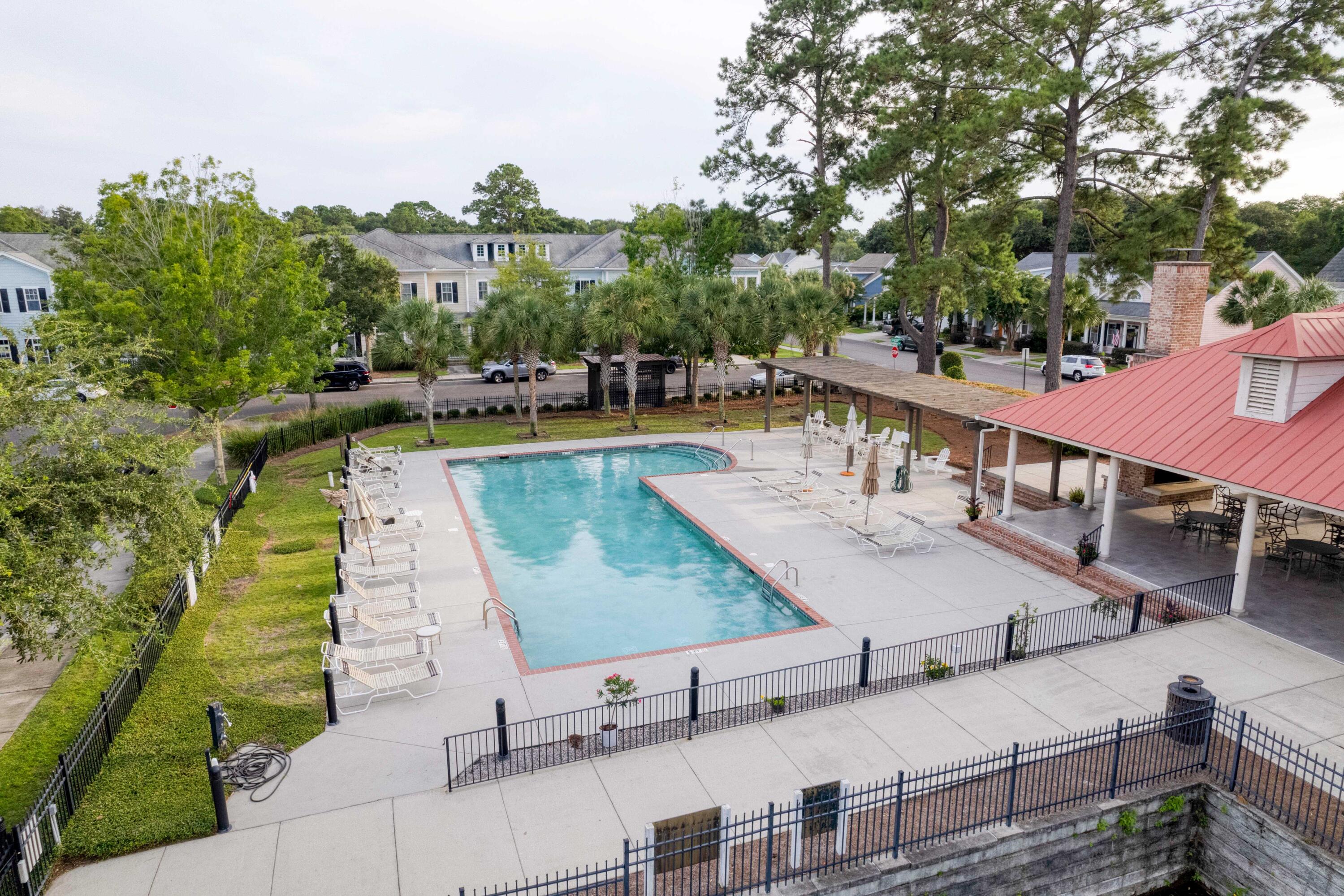 Neighborhood pool with lounge chairs and a covered pavilion with a red roof, viewed from above.