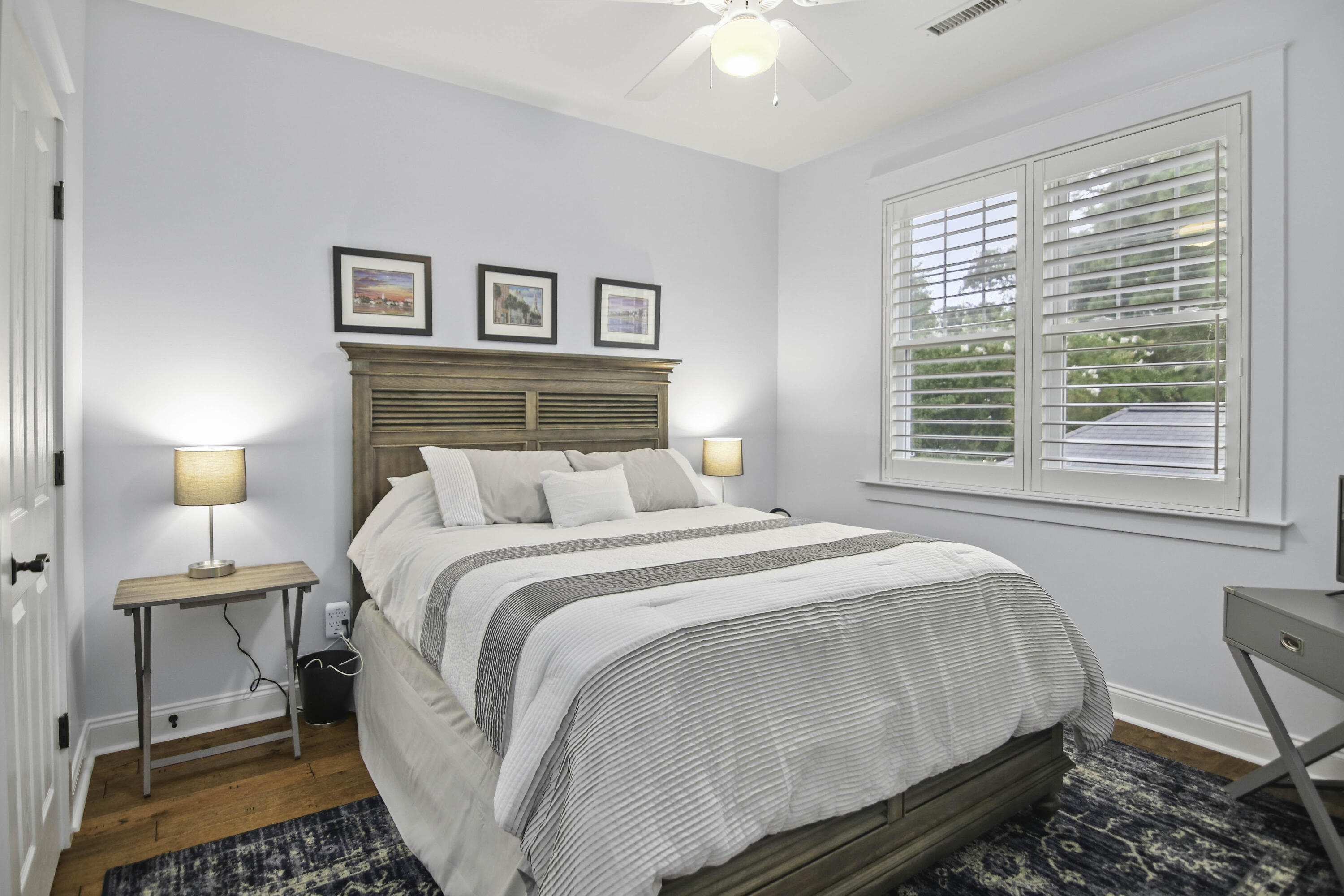 Bedroom with a large white-and-gray bed, wood headboard, and plantation-shuttered windows.