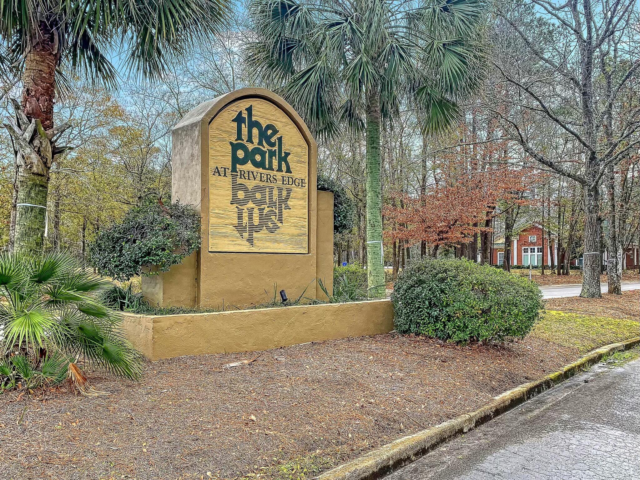 The Park at Rivers Edge entrance sign among palms and trees.
