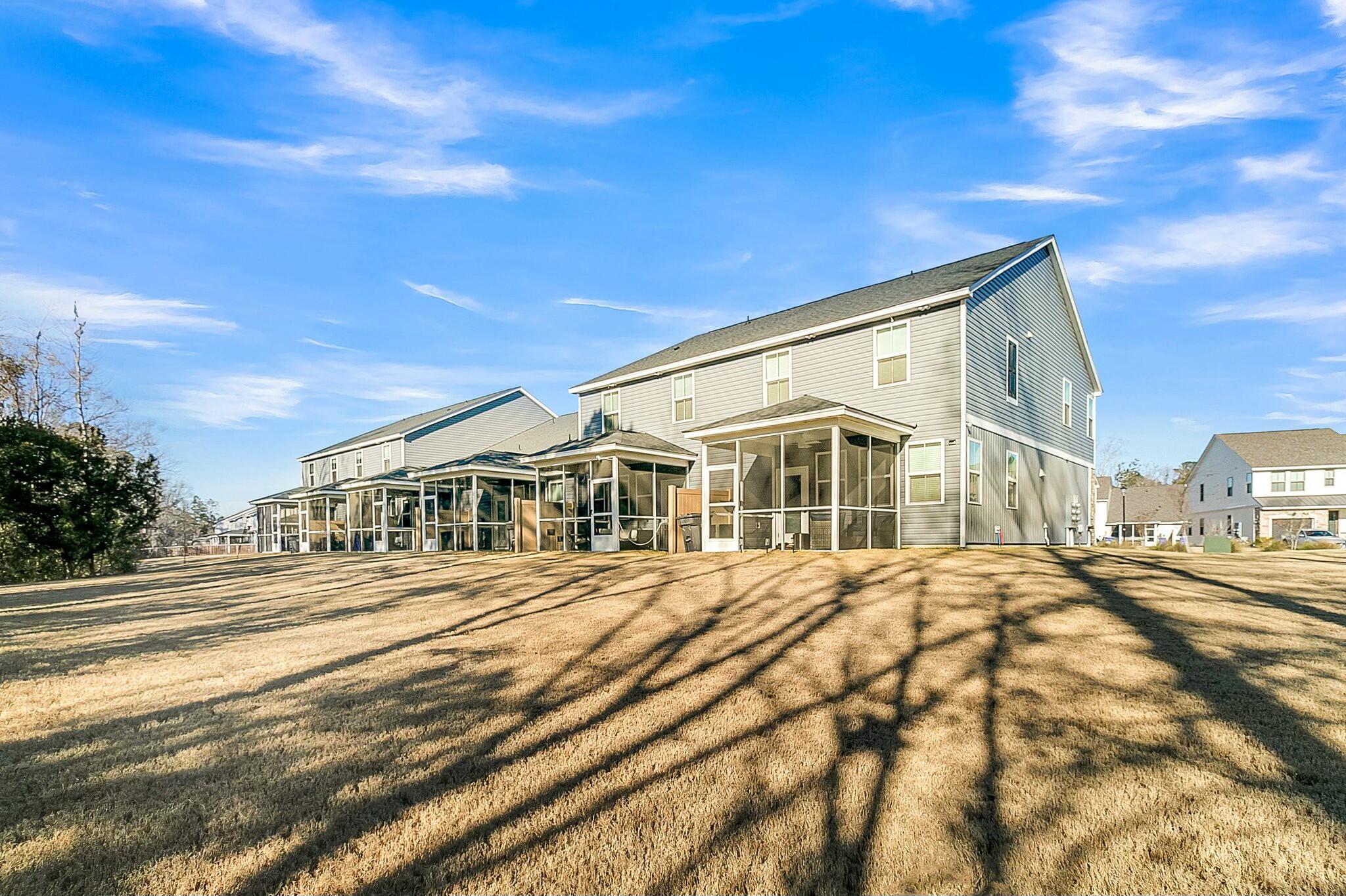Gray two-story house with a screened back porch overlooking a broad winter lawn.