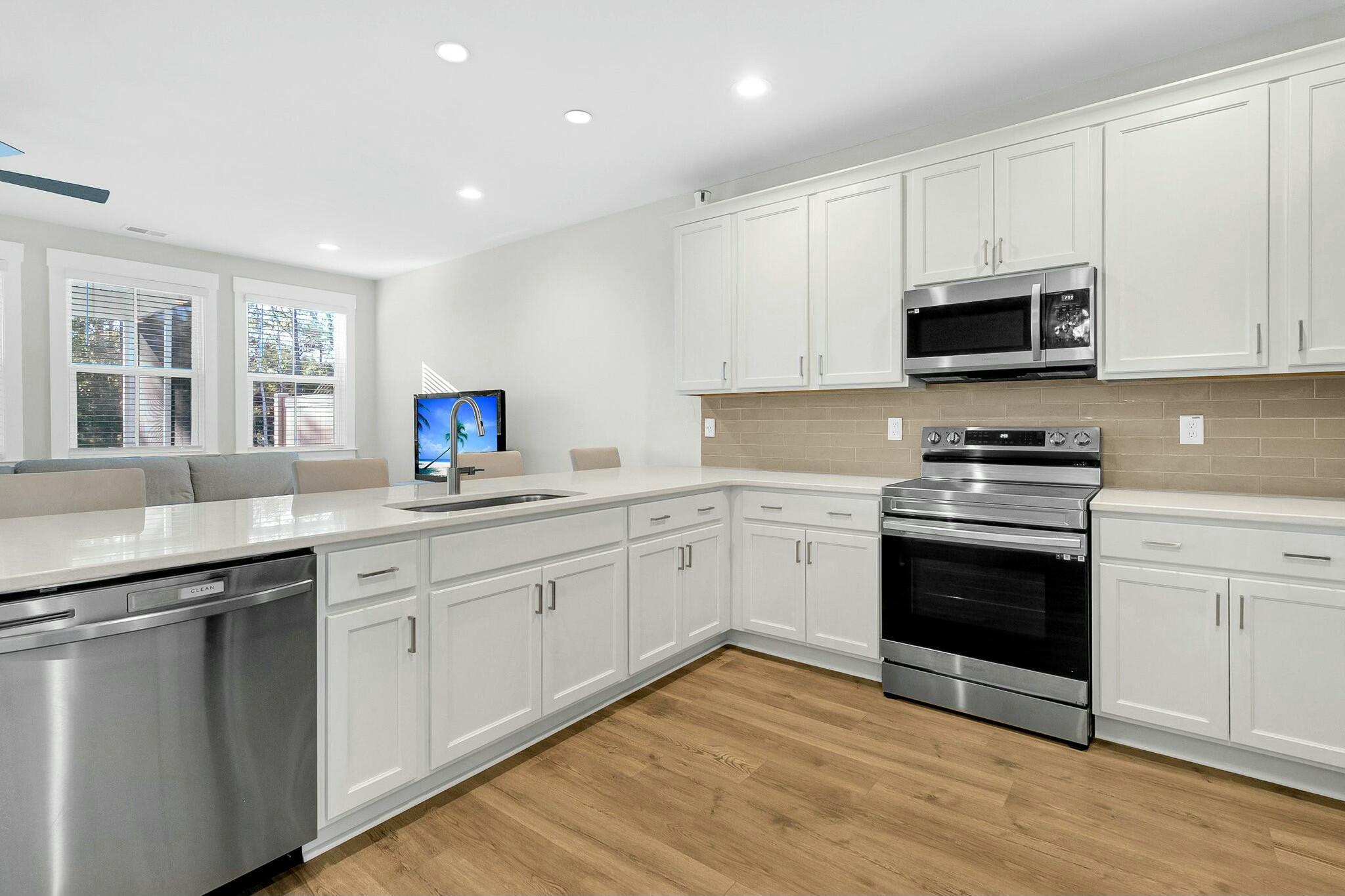 Bright kitchen with white cabinets, stainless steel appliances, and a large island.