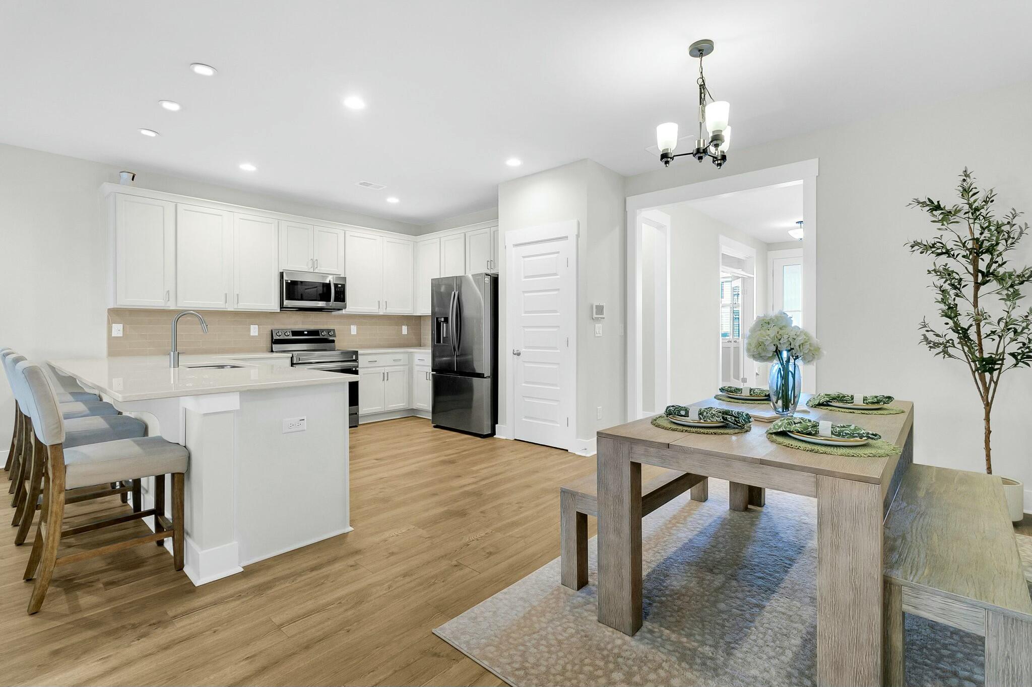 Open-plan kitchen and dining area with a white island, stainless appliances, and a set dining table.
