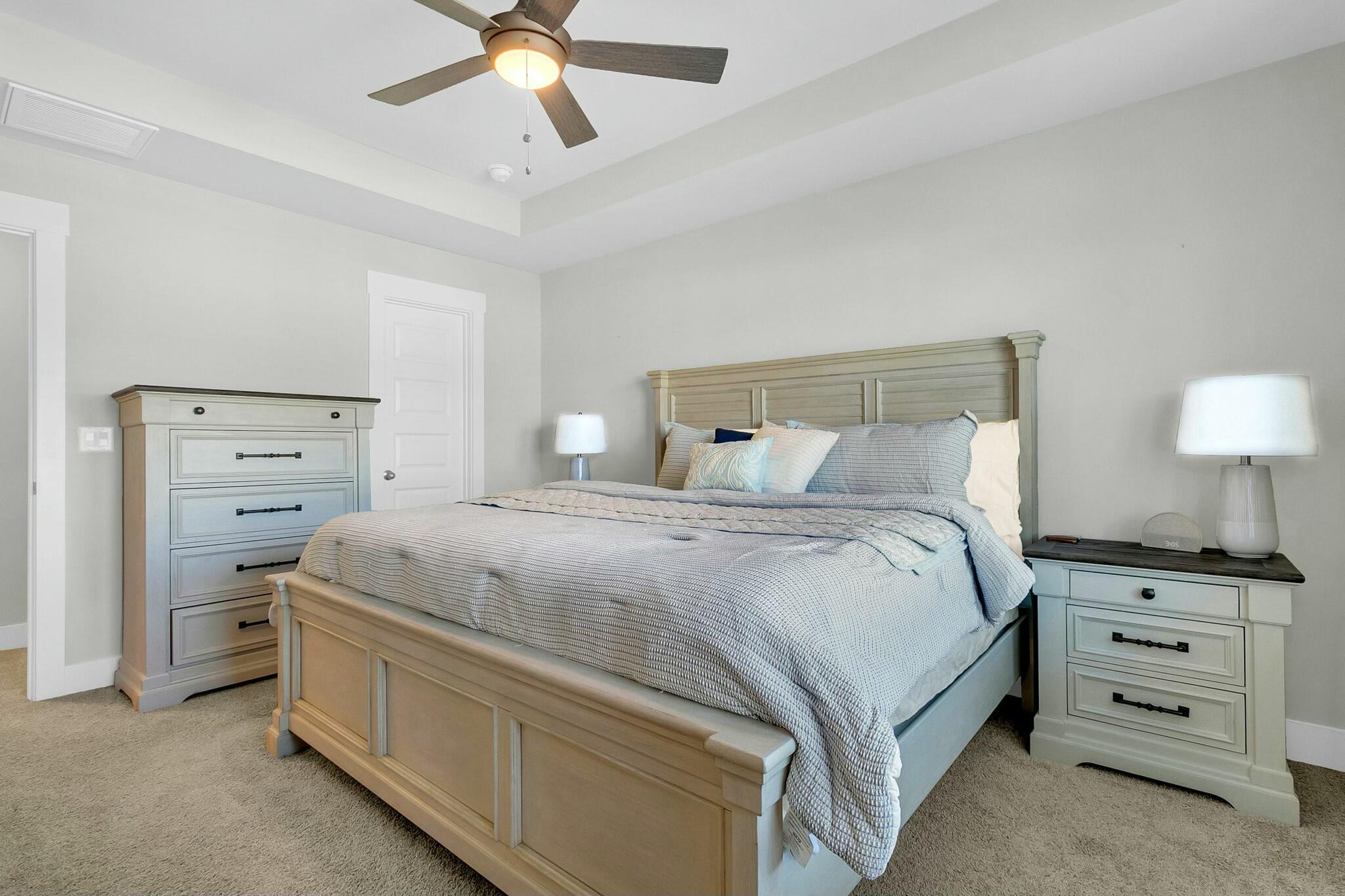 Bedroom with a large light blue and gray bed, matching dressers, and a ceiling fan.