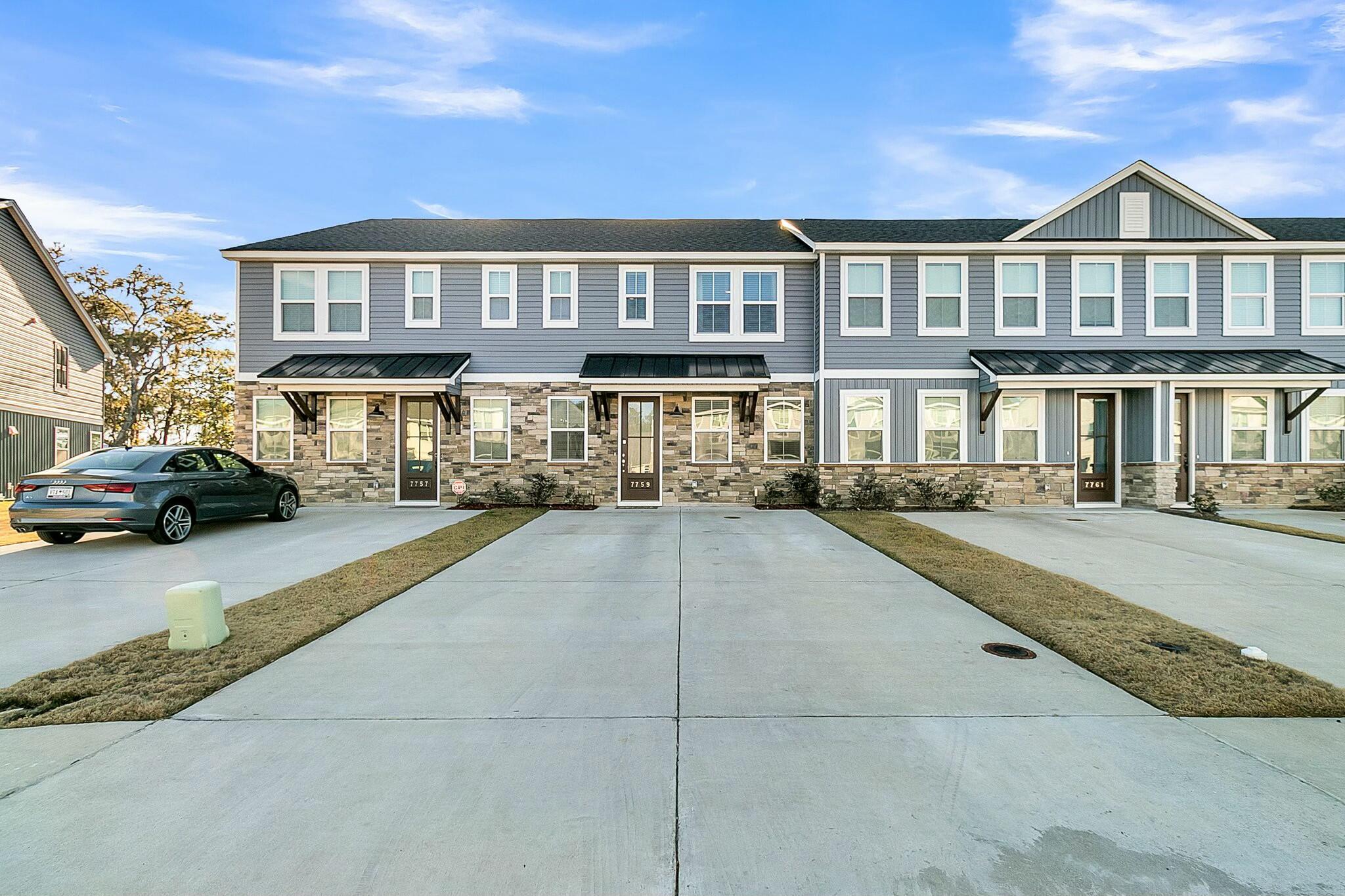 Townhome at 7759 Park Gate Drive with gray siding, stone facade, and a wide concrete driveway.