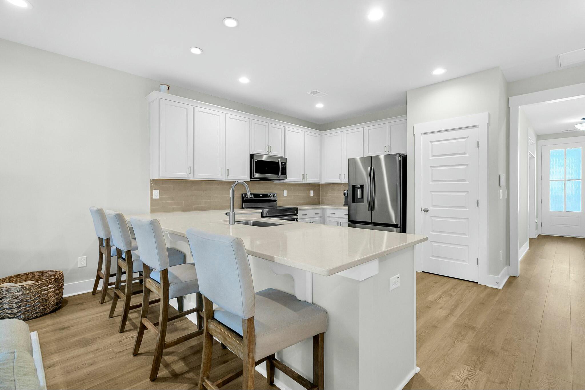 Kitchen with a large island, four counter stools, white cabinets, and stainless steel appliances.