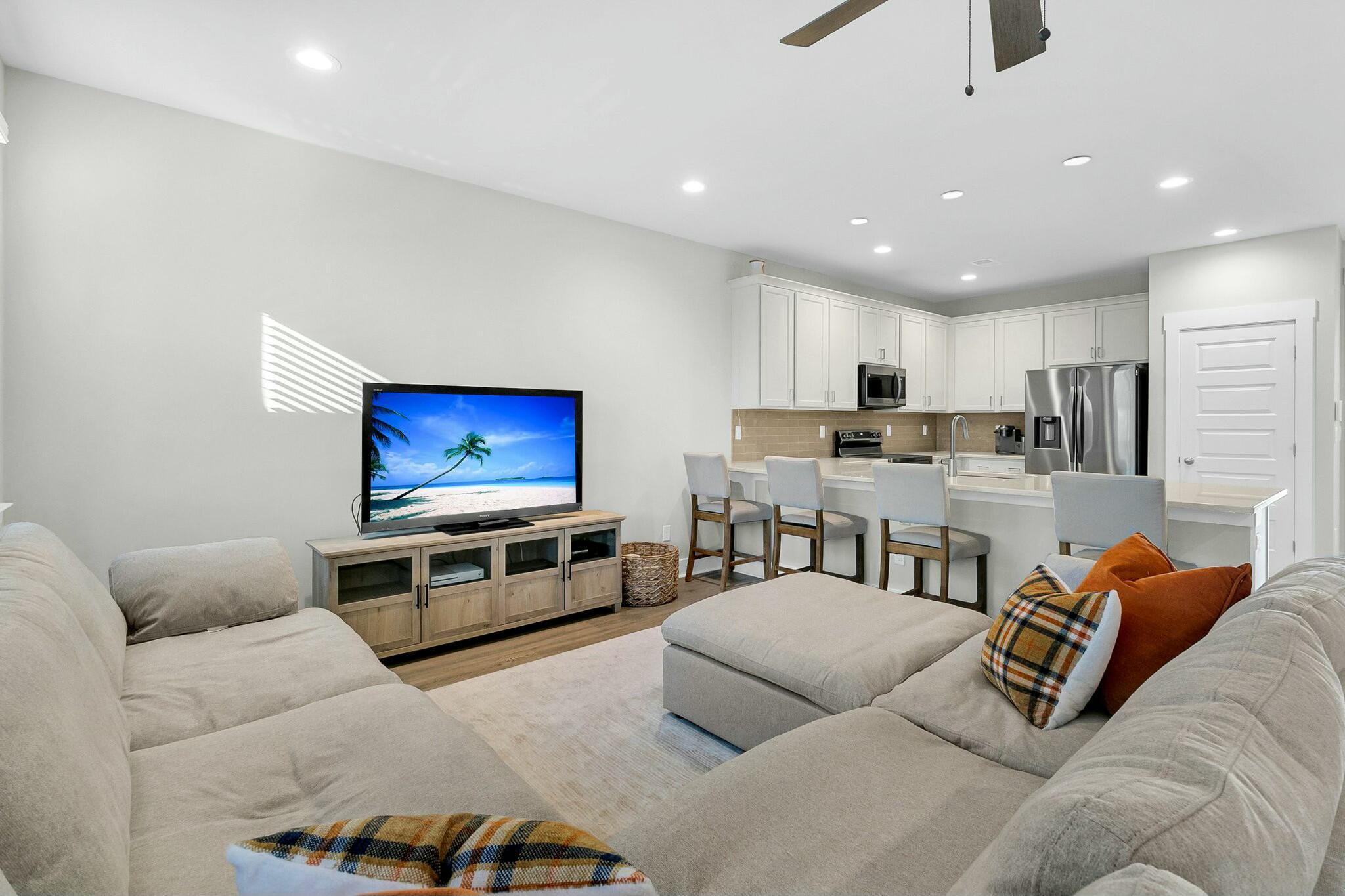 Furnished living room with a large sectional sofa facing an open kitchen and island.