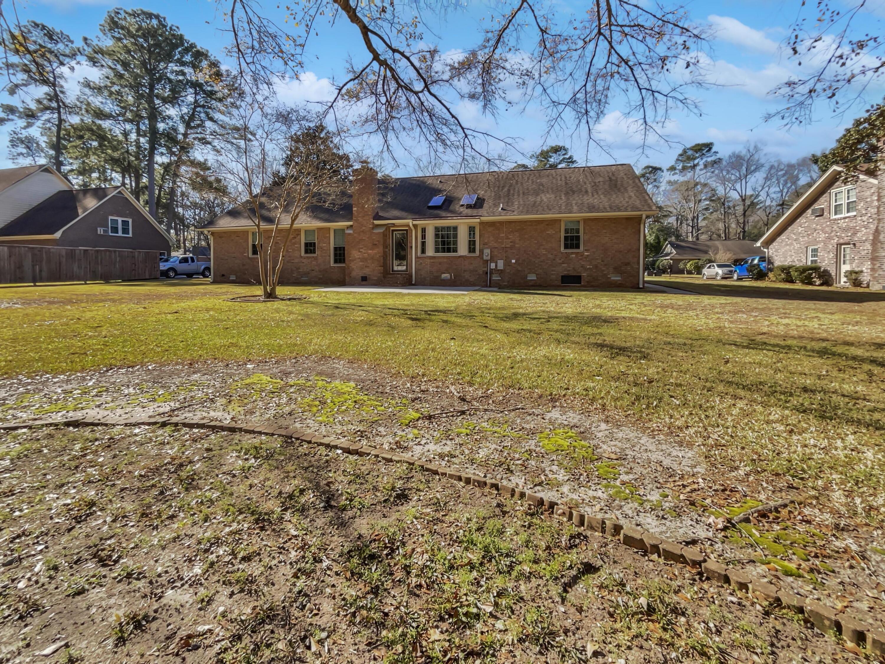 Rear of a brick ranch home with solar panels and a broad lawn.