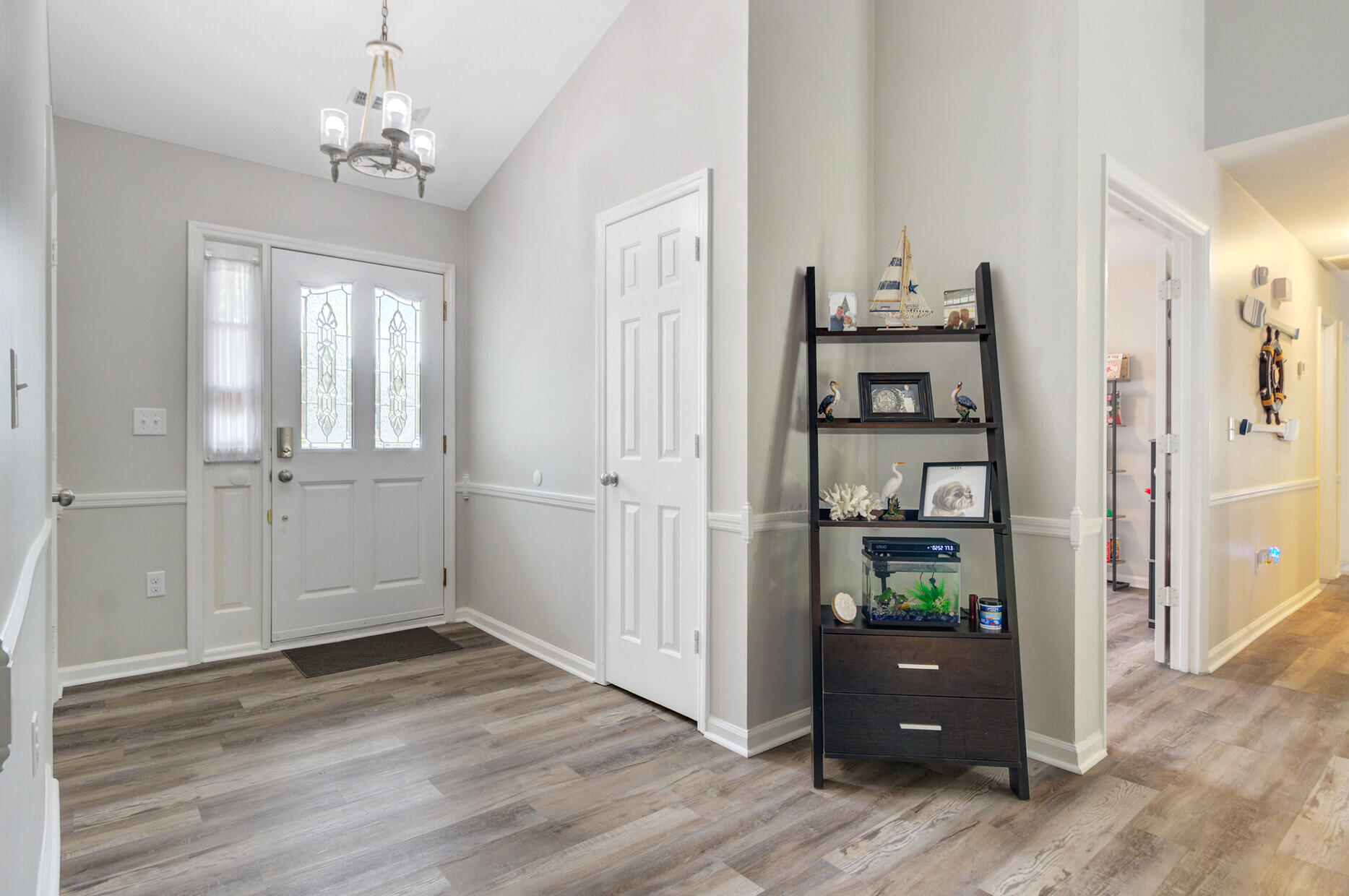 Furnished entryway with a glass-paneled front door, coastal display shelf, and small aquarium.
