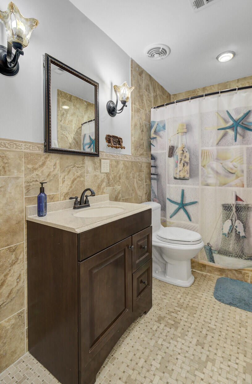 Bathroom with a dark wood vanity, tan tile walls, and a starfish-patterned shower curtain.