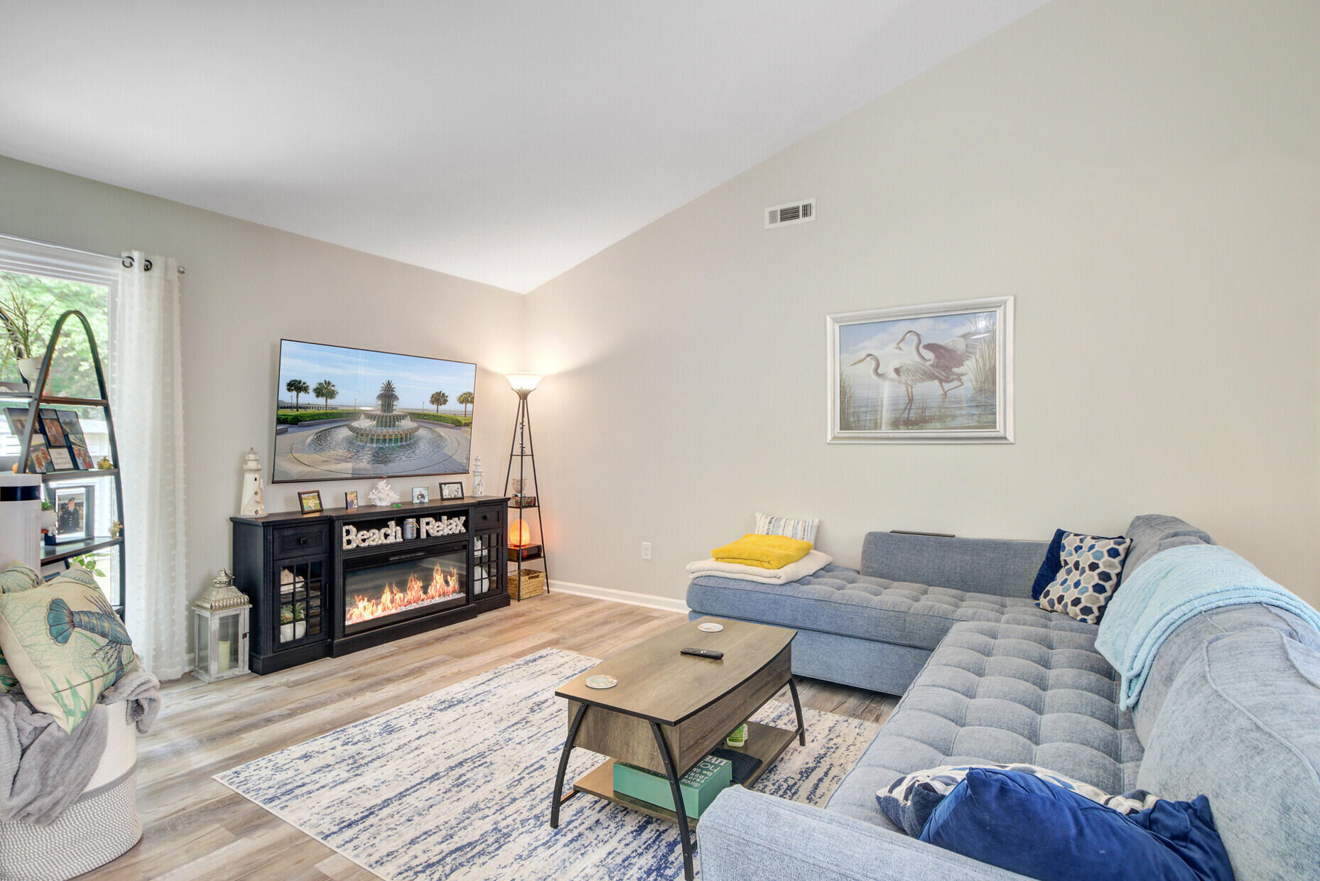 Living room with a blue sectional, patterned rug, and black media cabinet with an electric fireplace.
