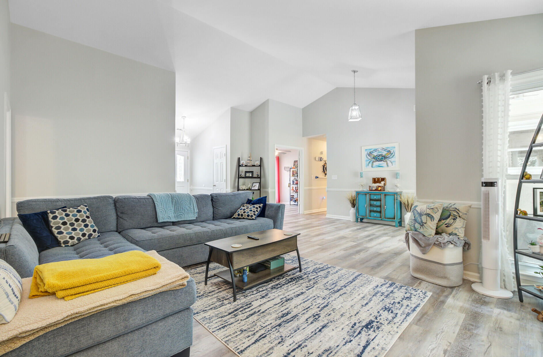 Furnished living room with a gray sectional, patterned rug, and turquoise console.