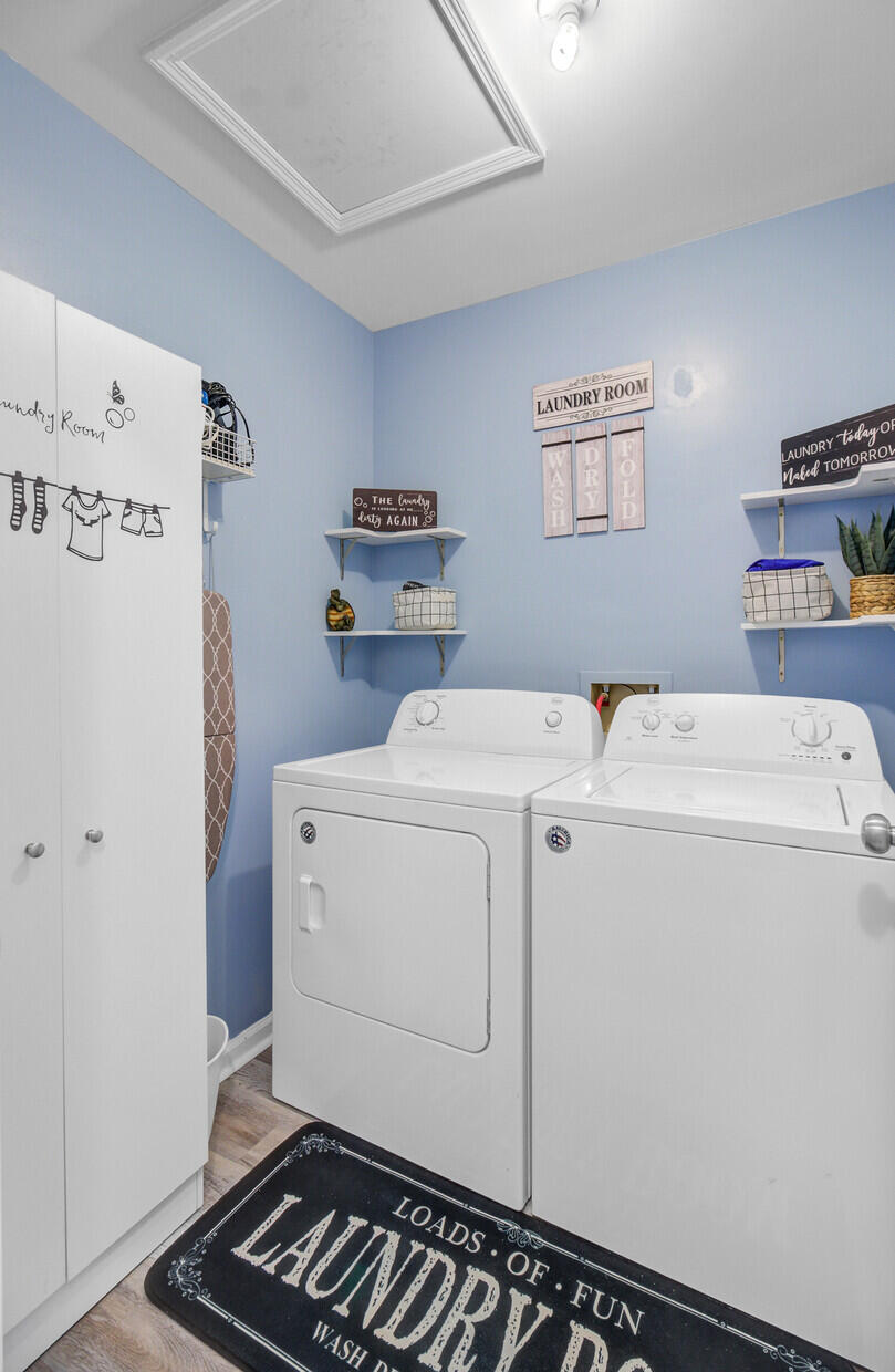 Laundry room with white washer and dryer, blue walls, wall shelves, and a tall storage cabinet.
