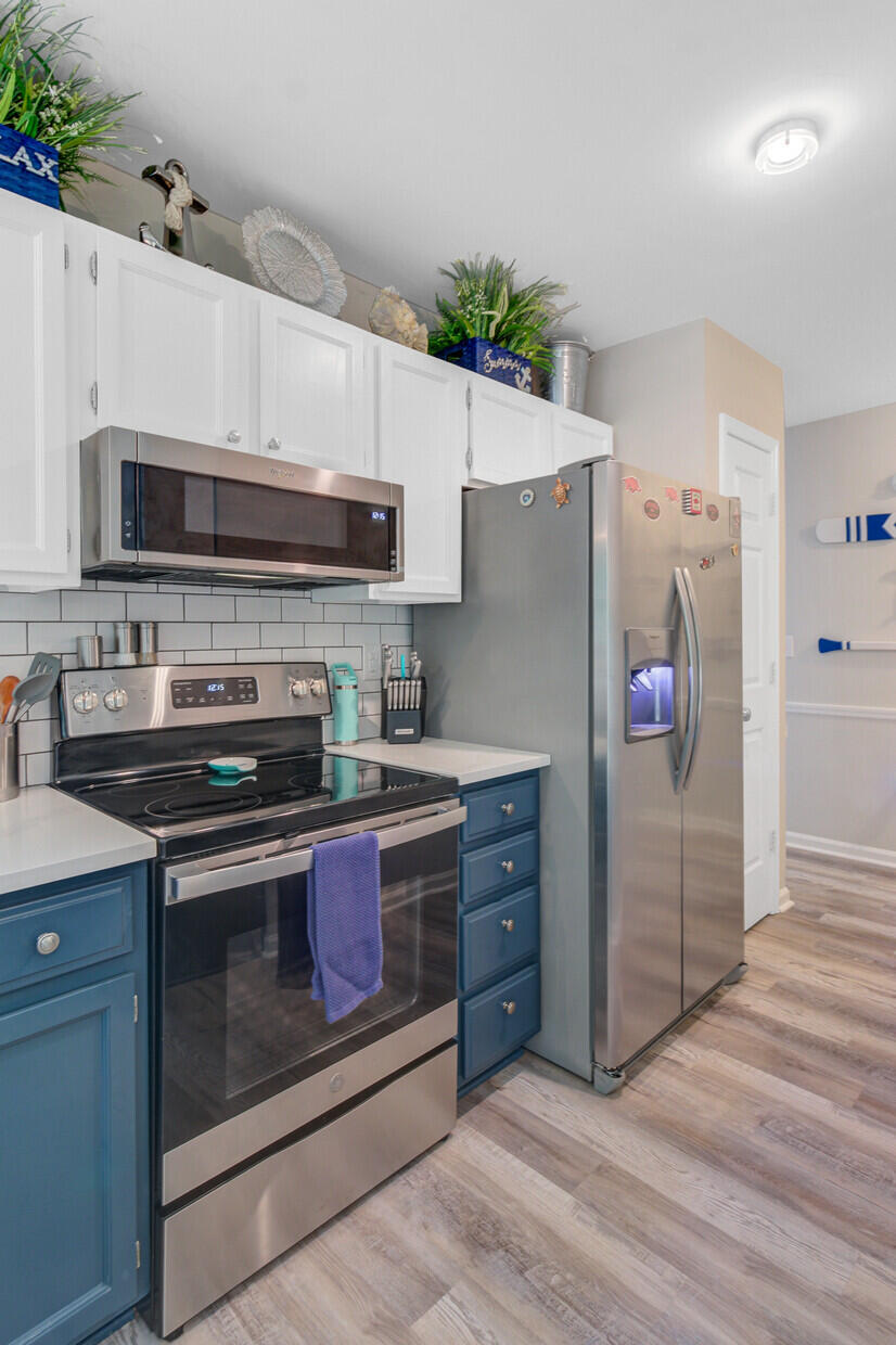 Kitchen with blue lower cabinets, white upper cabinets, and stainless steel appliances.