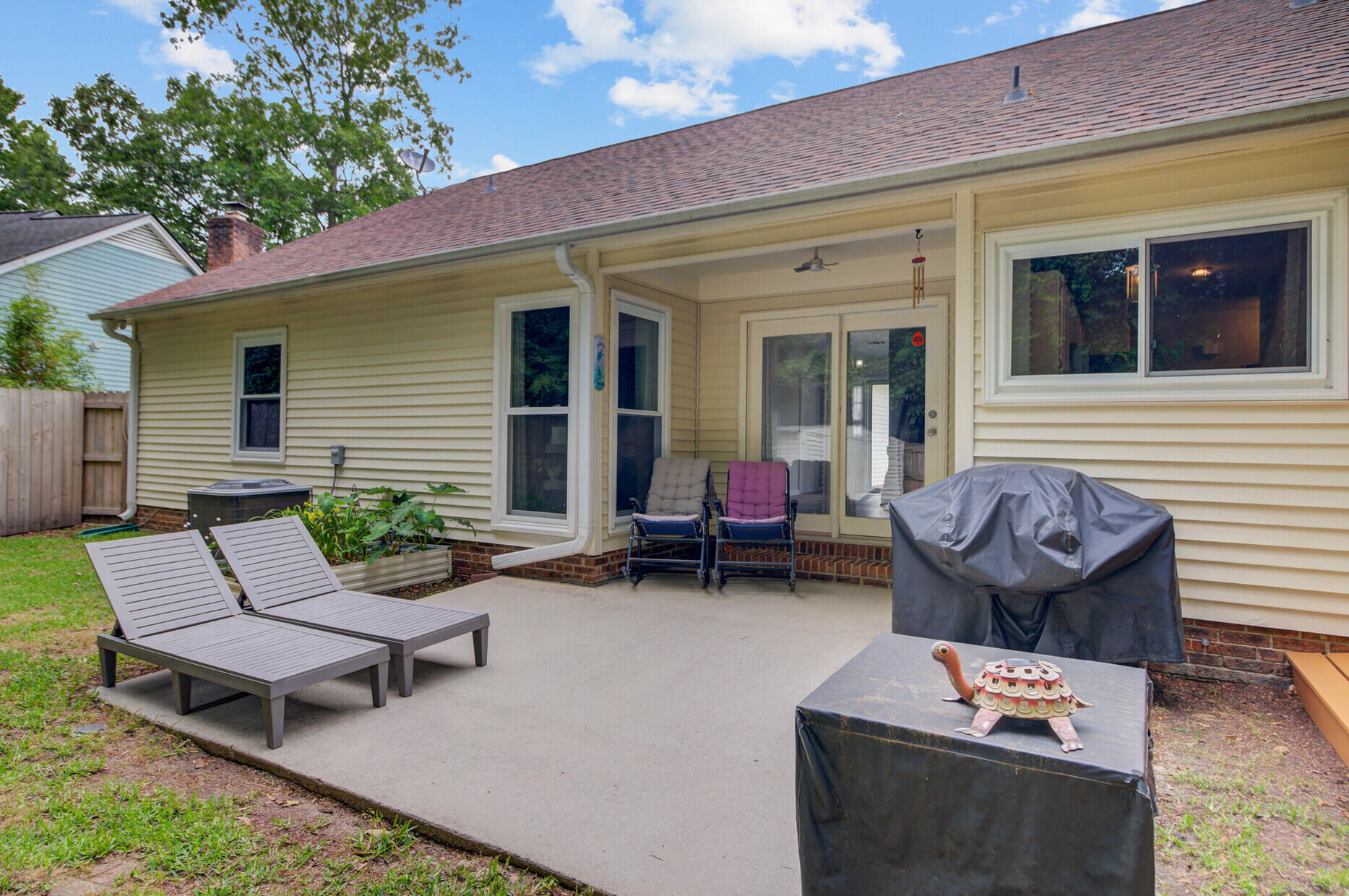 Rear patio with covered seating area, sliding glass door, lounge chairs, and a covered grill.