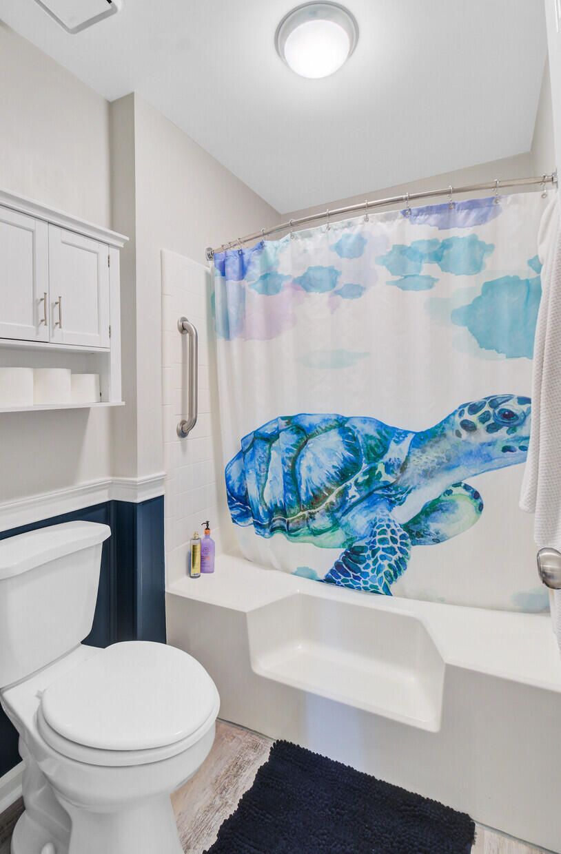 Bathroom with a white tub, navy wall paneling, and a sea turtle shower curtain.