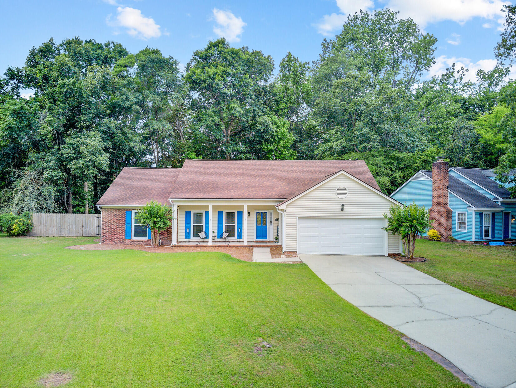 One-story home with a covered porch, blue front door, attached garage, and broad front lawn.