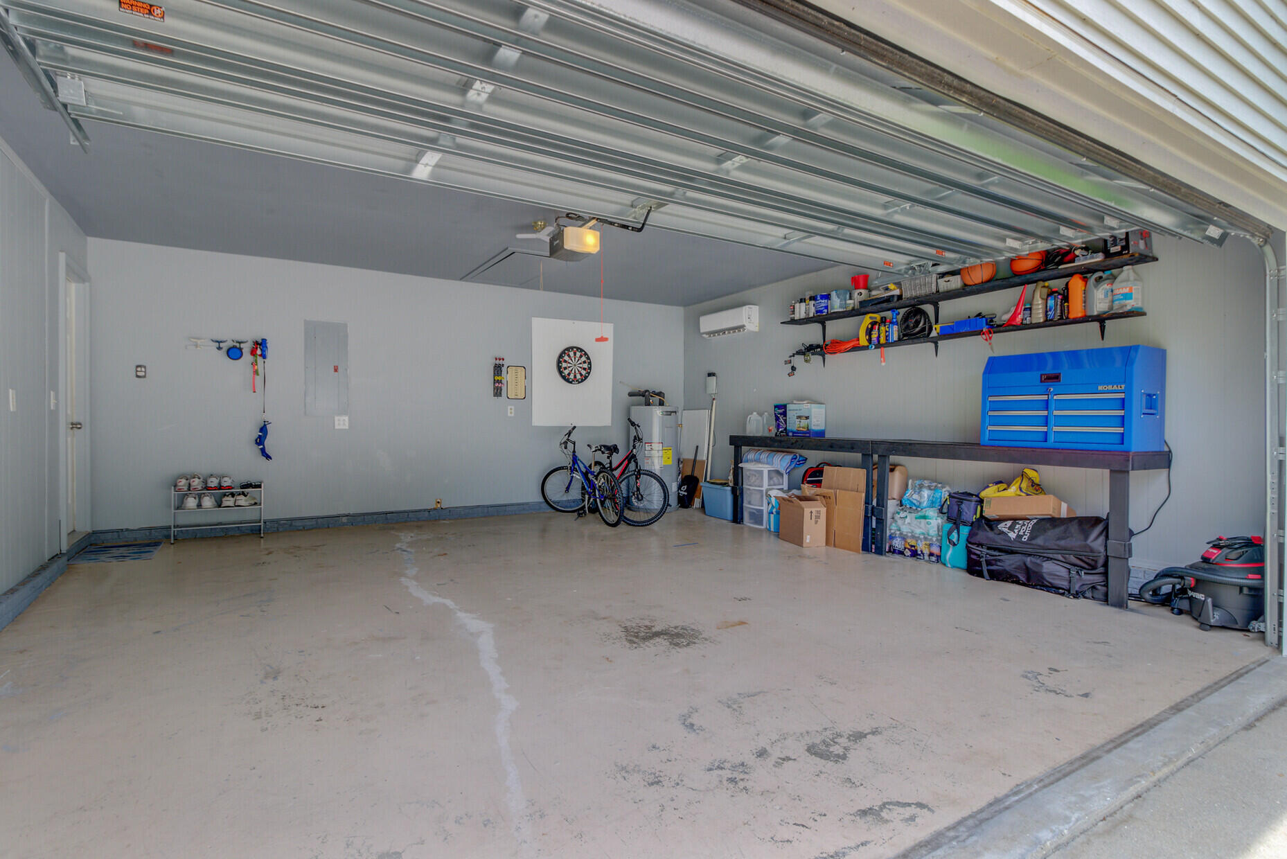 Spacious garage with a blue tool chest, bicycles, storage shelves, and a wide concrete floor.
