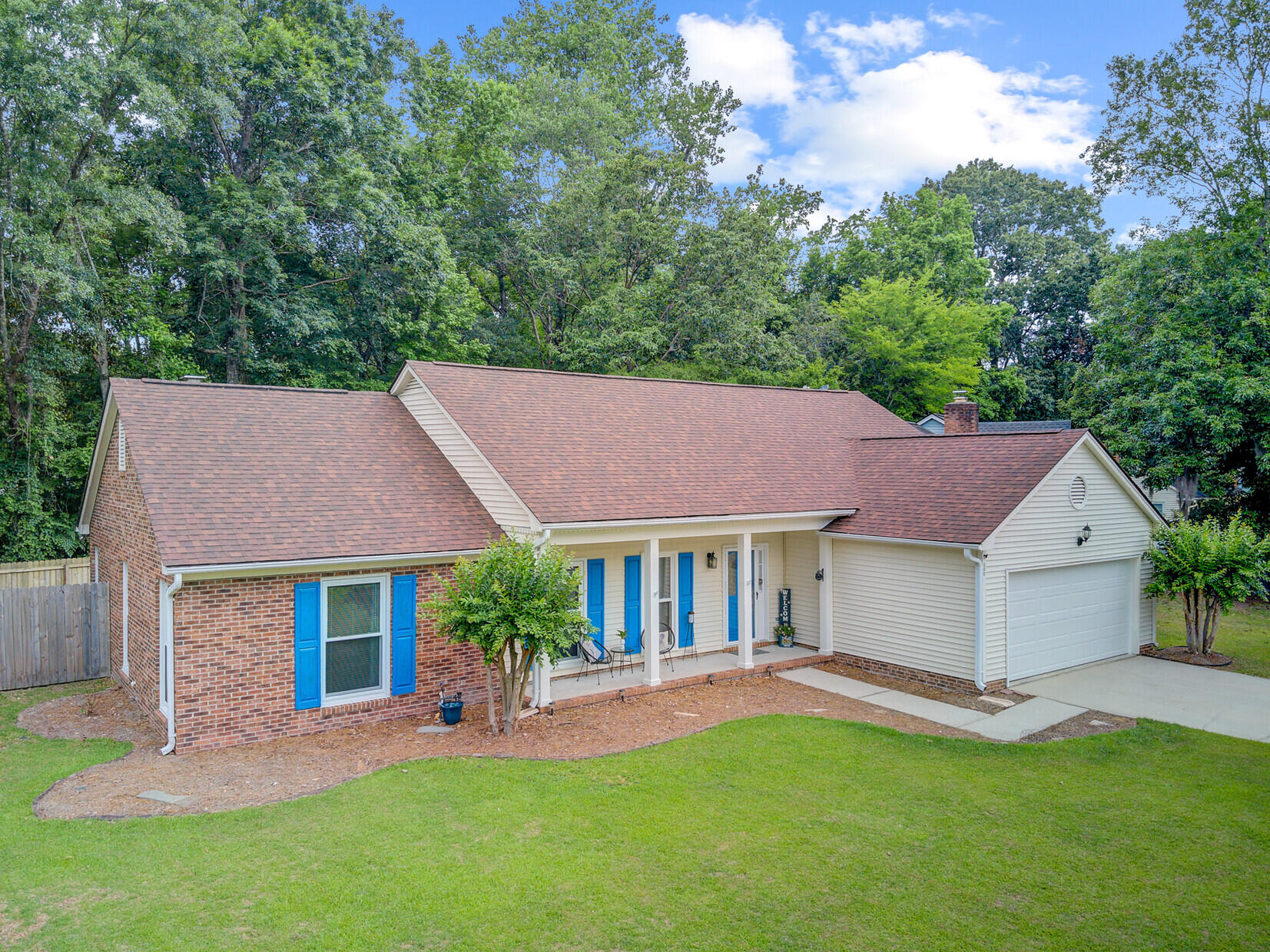 Single-story brick and siding home with blue shutters, a covered porch, and an attached garage.