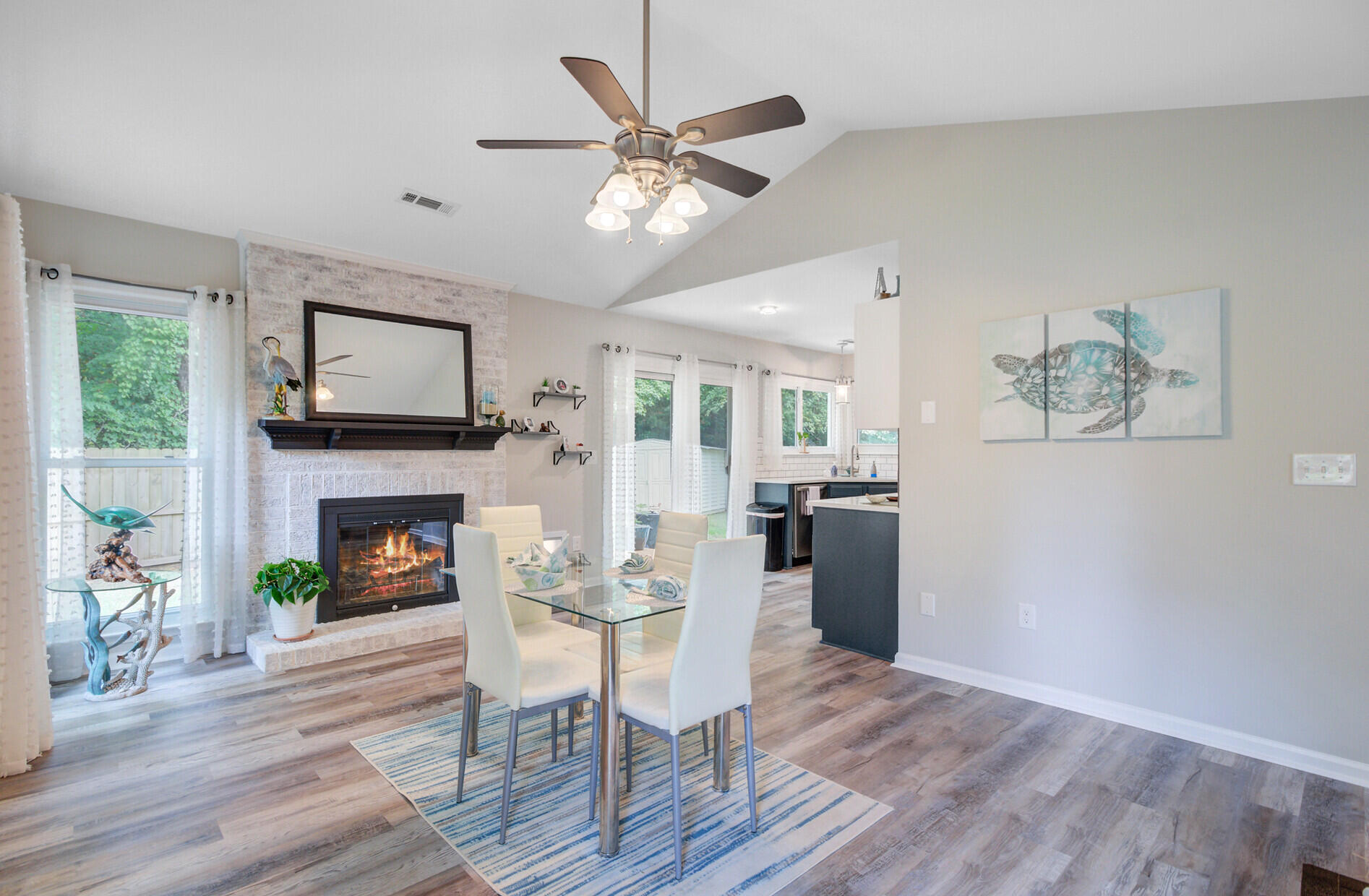 Open living and dining area with a white brick fireplace and glass dining table.