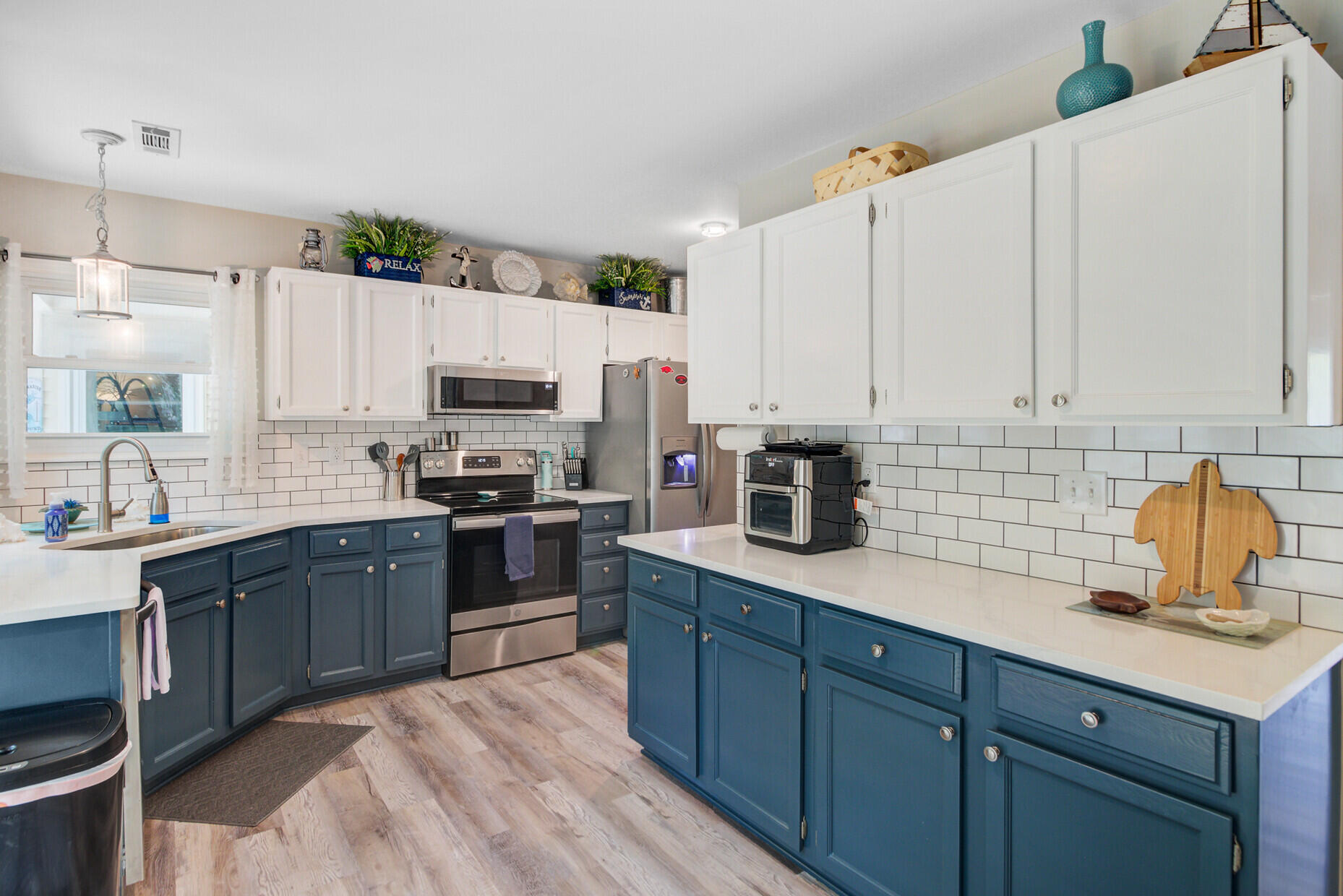 Kitchen with blue lower cabinets, white subway-tile backsplash, and stainless steel appliances.