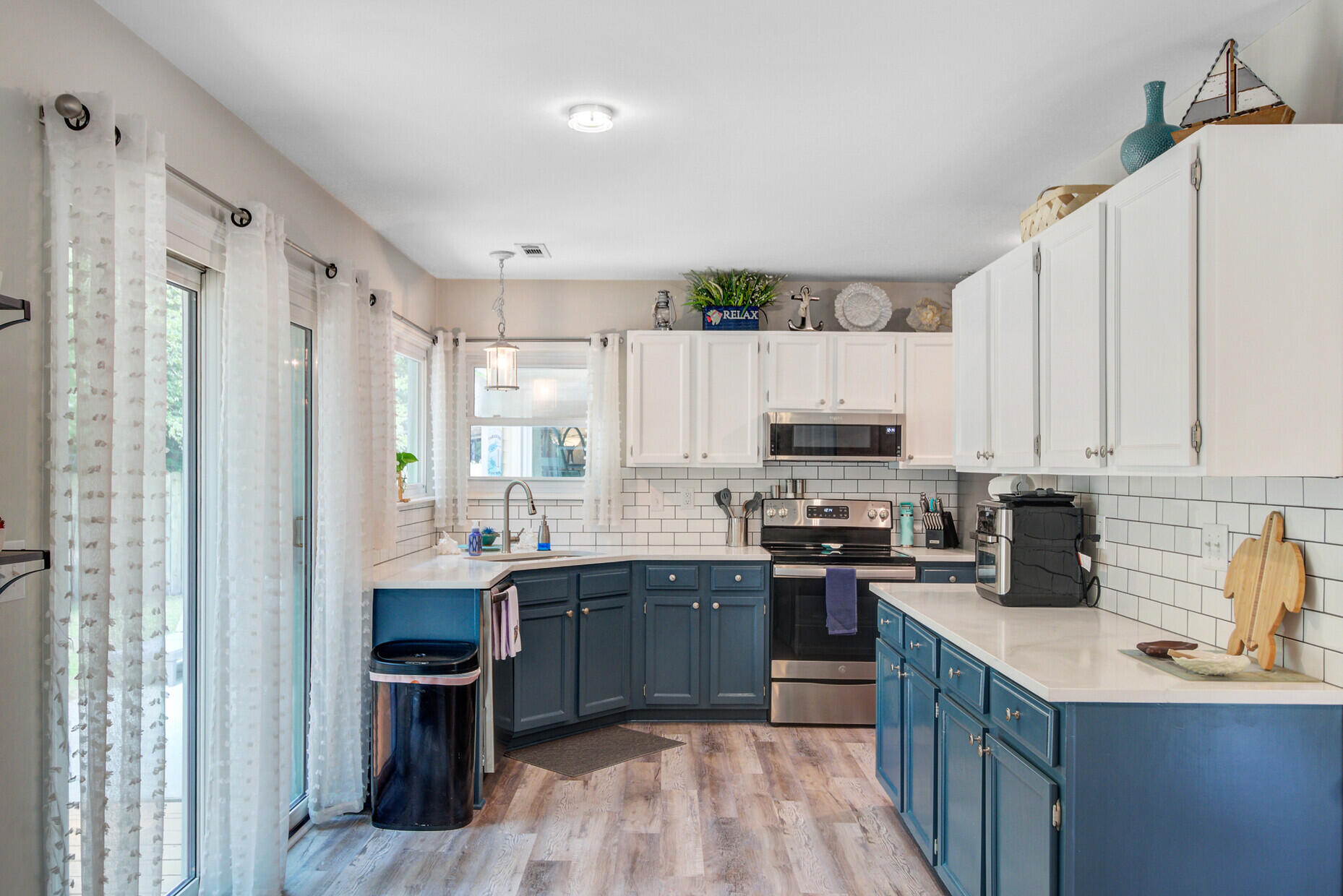 Kitchen with blue cabinets, white subway tile backsplash, and stainless steel appliances.