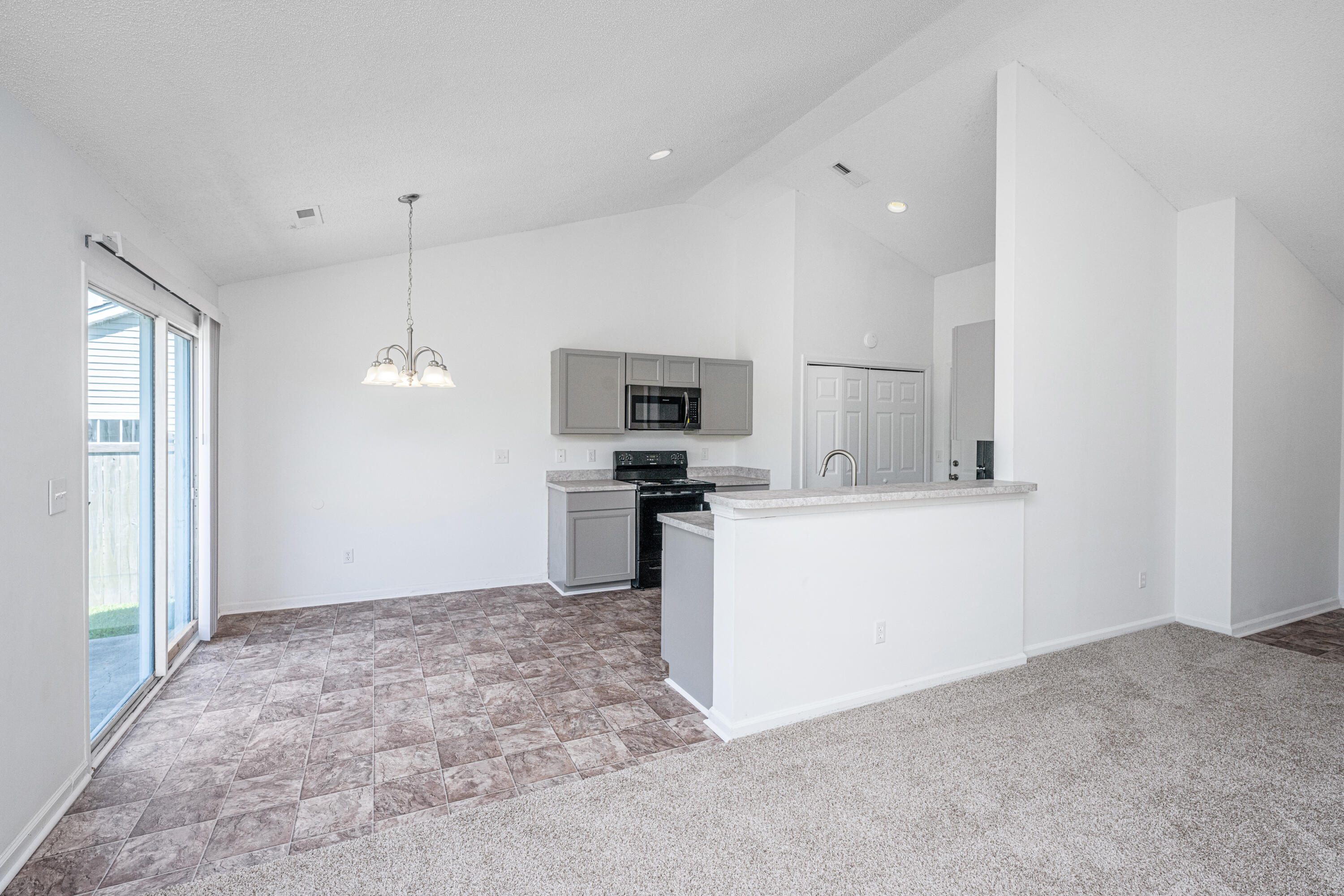 Open kitchen with gray cabinets, a breakfast bar, tiled floor, and sliding glass door.