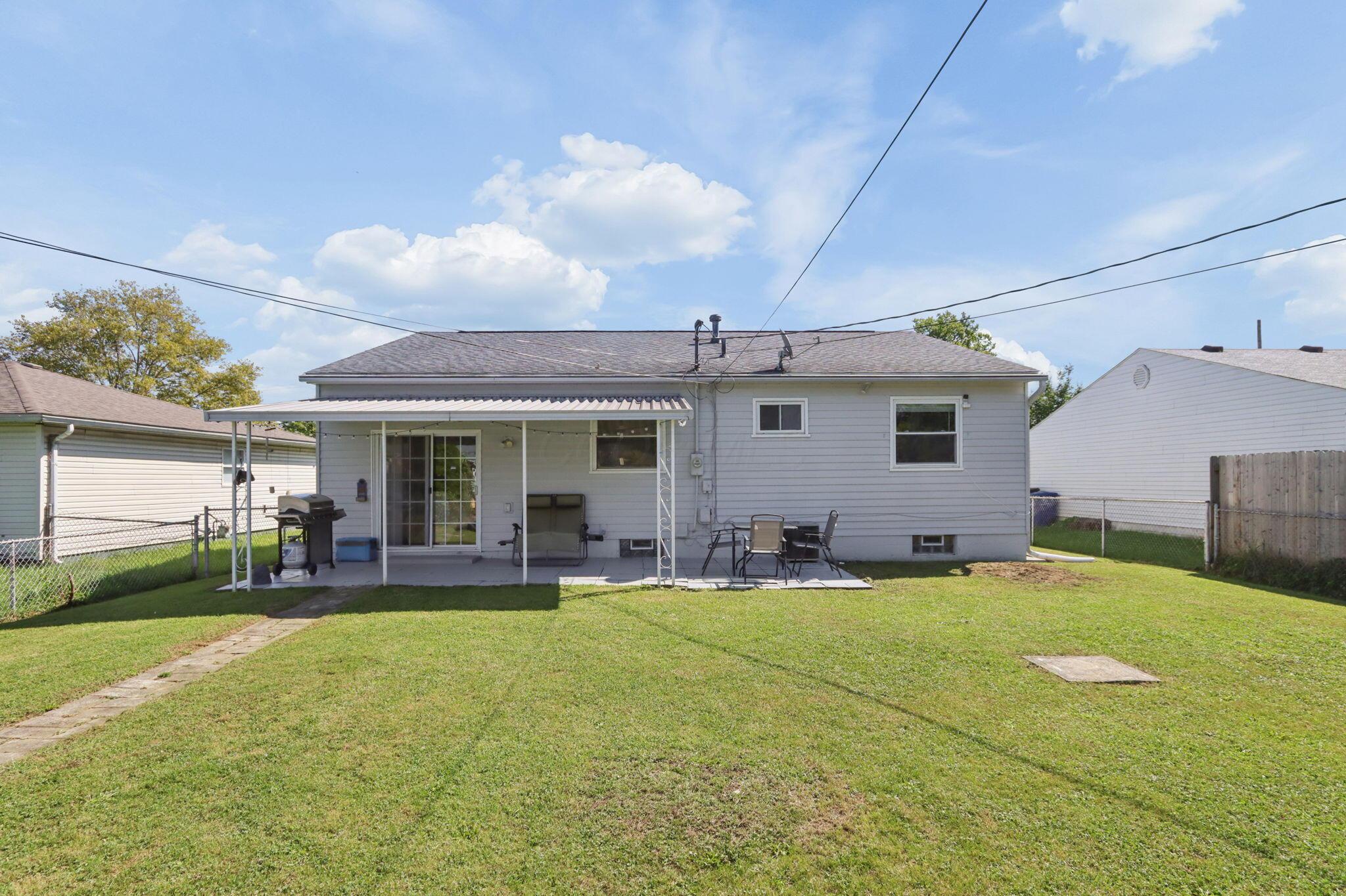 Gray-sided home with covered patio and fenced backyard lawn.