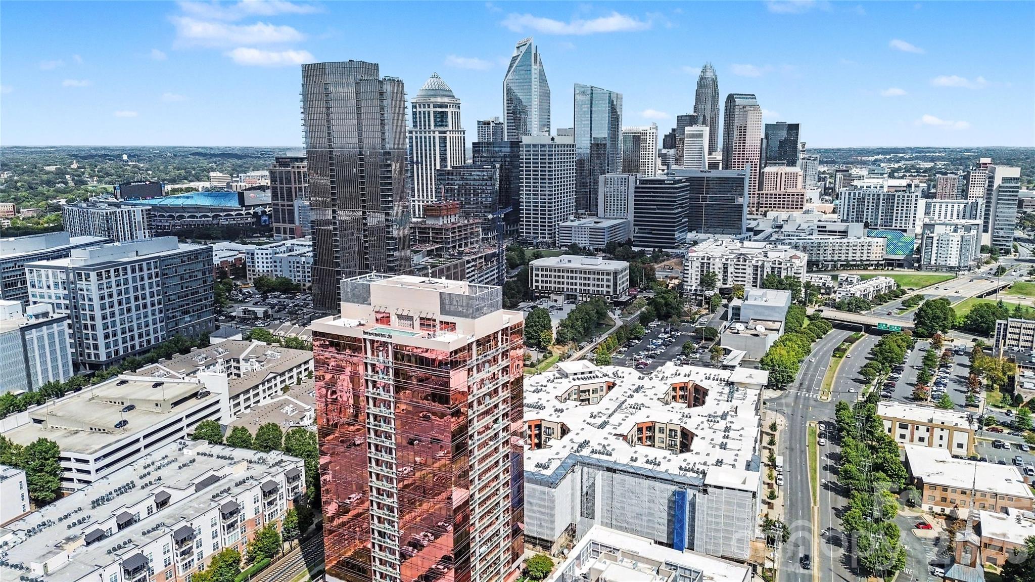 Aerial view of Charlotte’s downtown skyline, with high-rises, a stadium, and tree-lined roads.