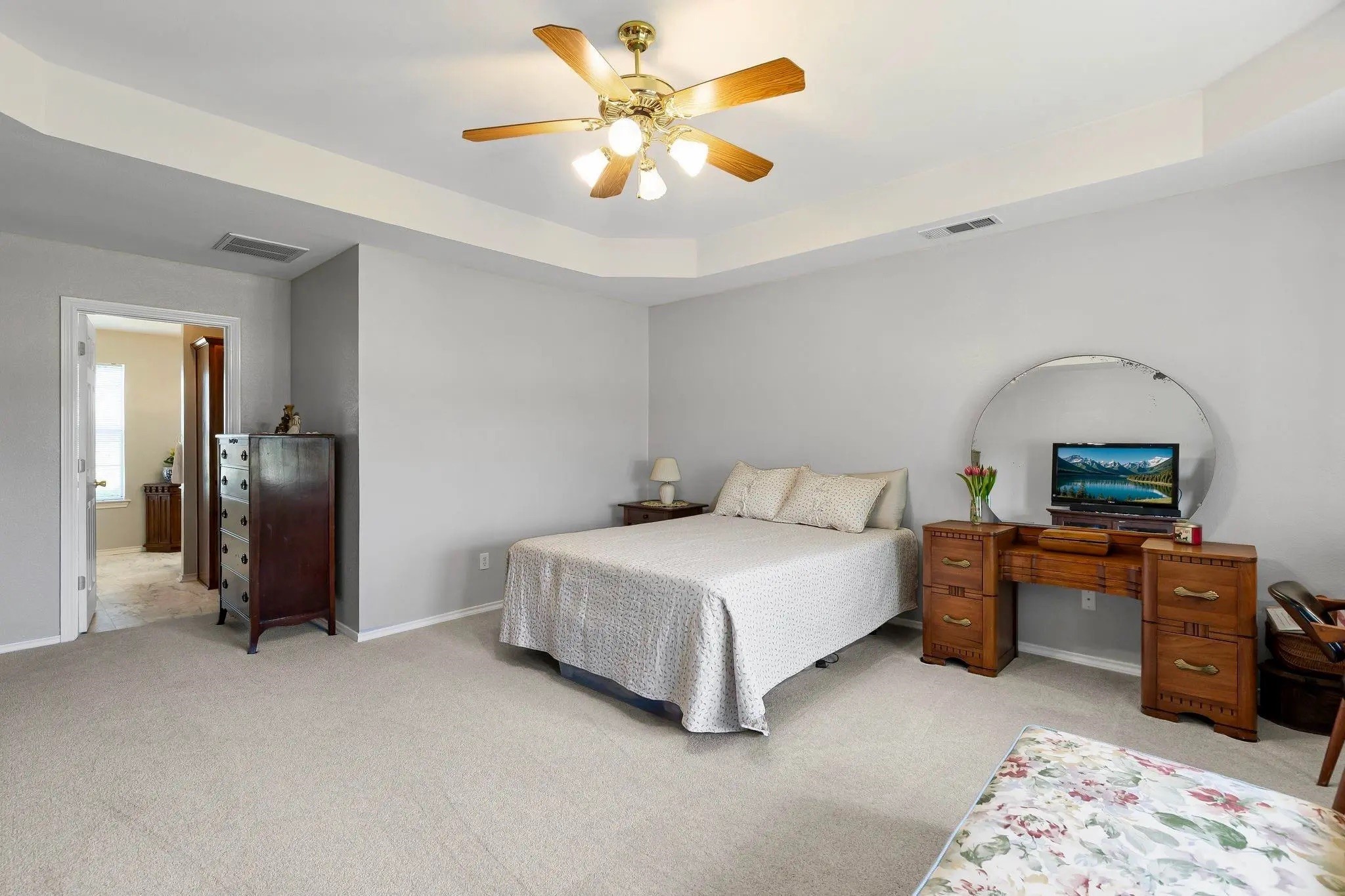 Furnished bedroom with a large bed, wooden vanity, and ceiling fan.