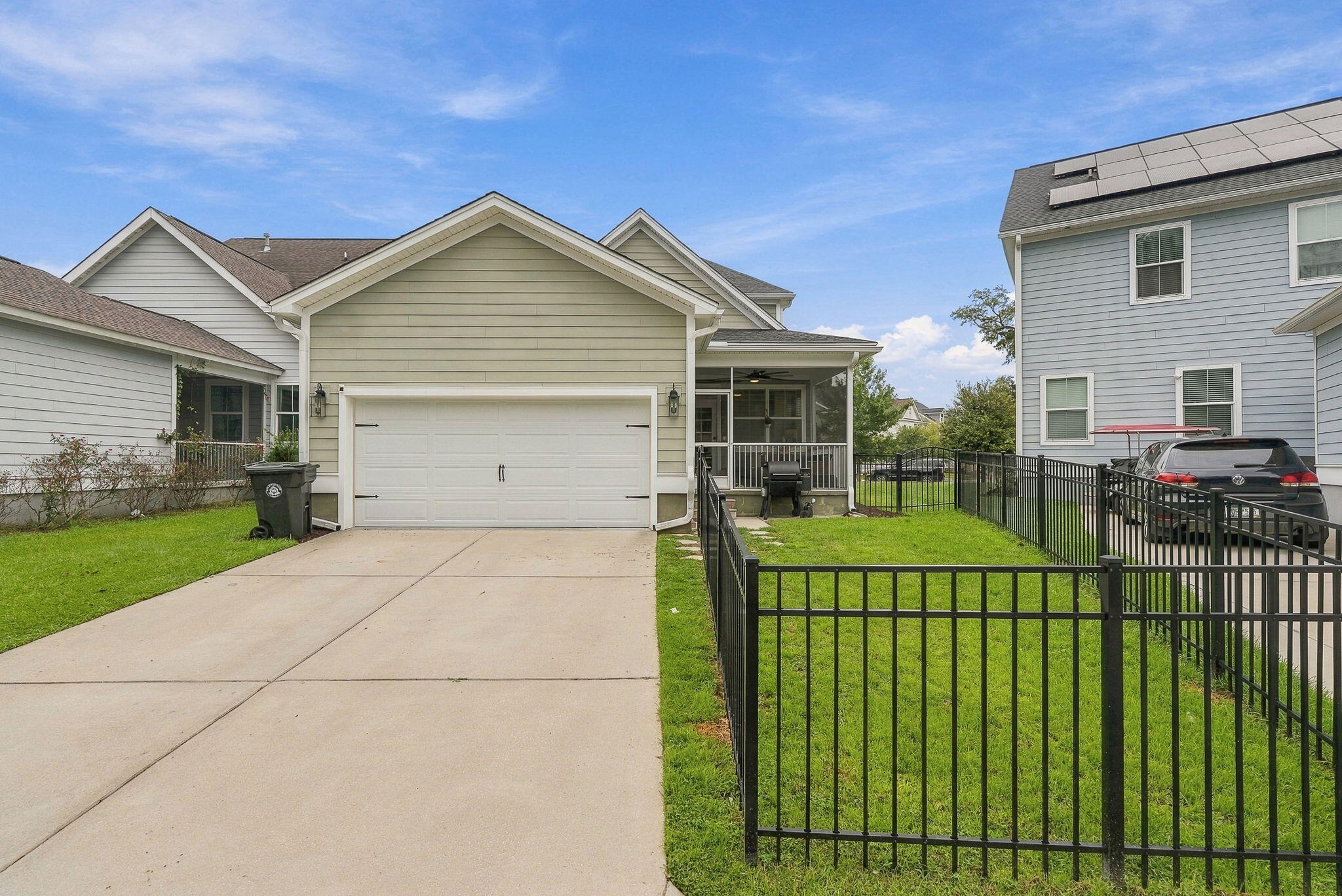 Home exterior with a double garage, wide driveway, covered porch, and fenced lawn.