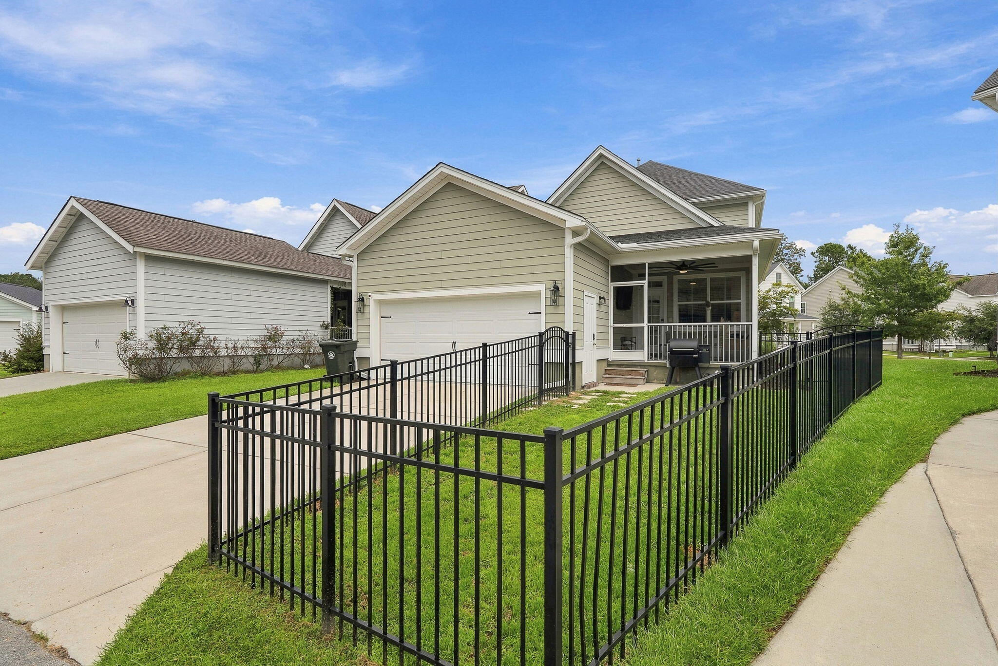 House exterior with a screened porch, attached garage, and fenced grassy yard.