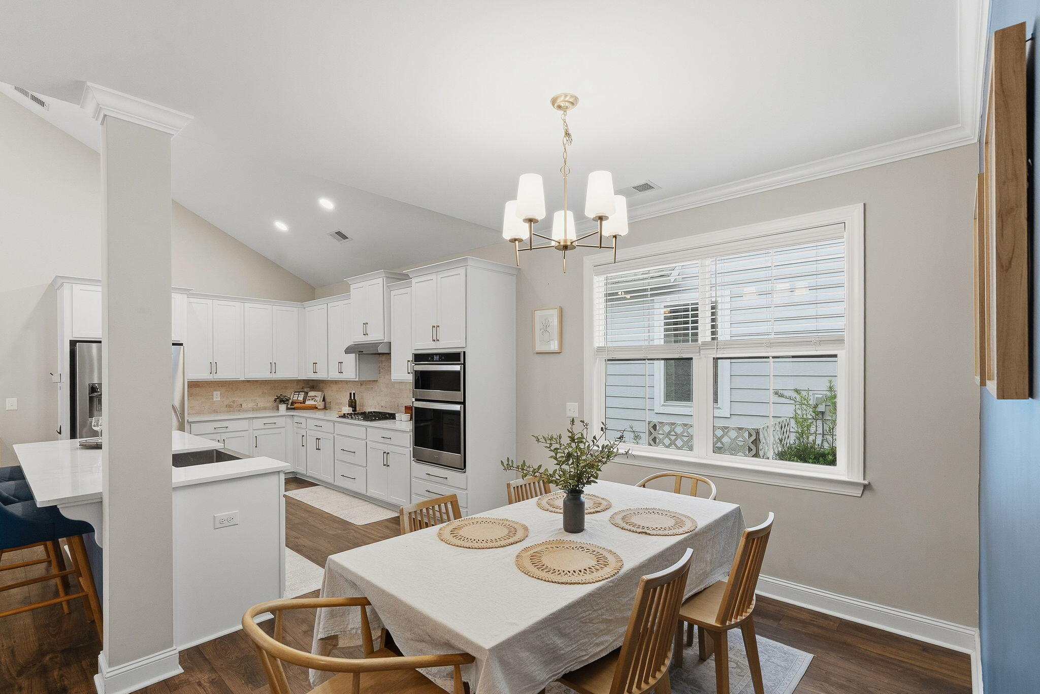 Kitchen and dining area with white cabinets, stainless appliances, and a set dining table by the window.