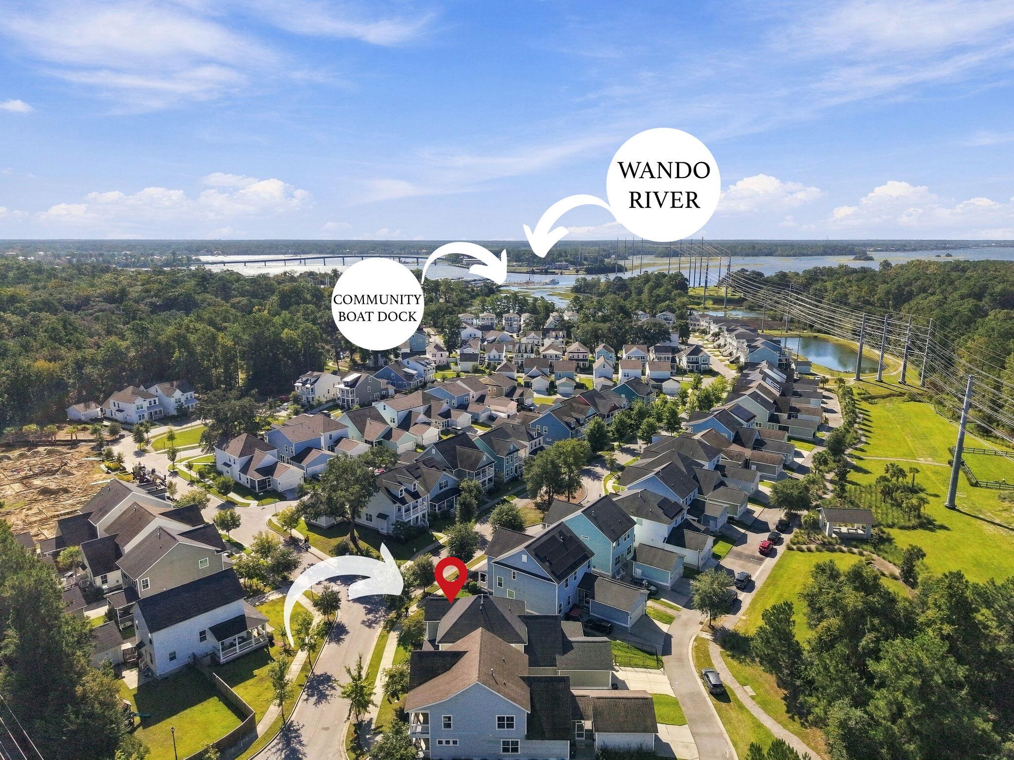 Aerial view of the neighborhood and marked home, with the community boat dock and Wando River.